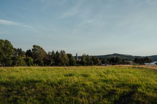 Free Expansive green field under clear sky in a rural setting, surrounded by trees. Stock Photo