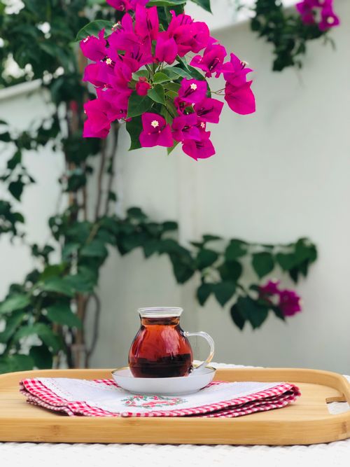 Free A serene outdoor tea setting with vibrant pink bougainvillea flowers creating a picturesque atmosphere. Stock Photo