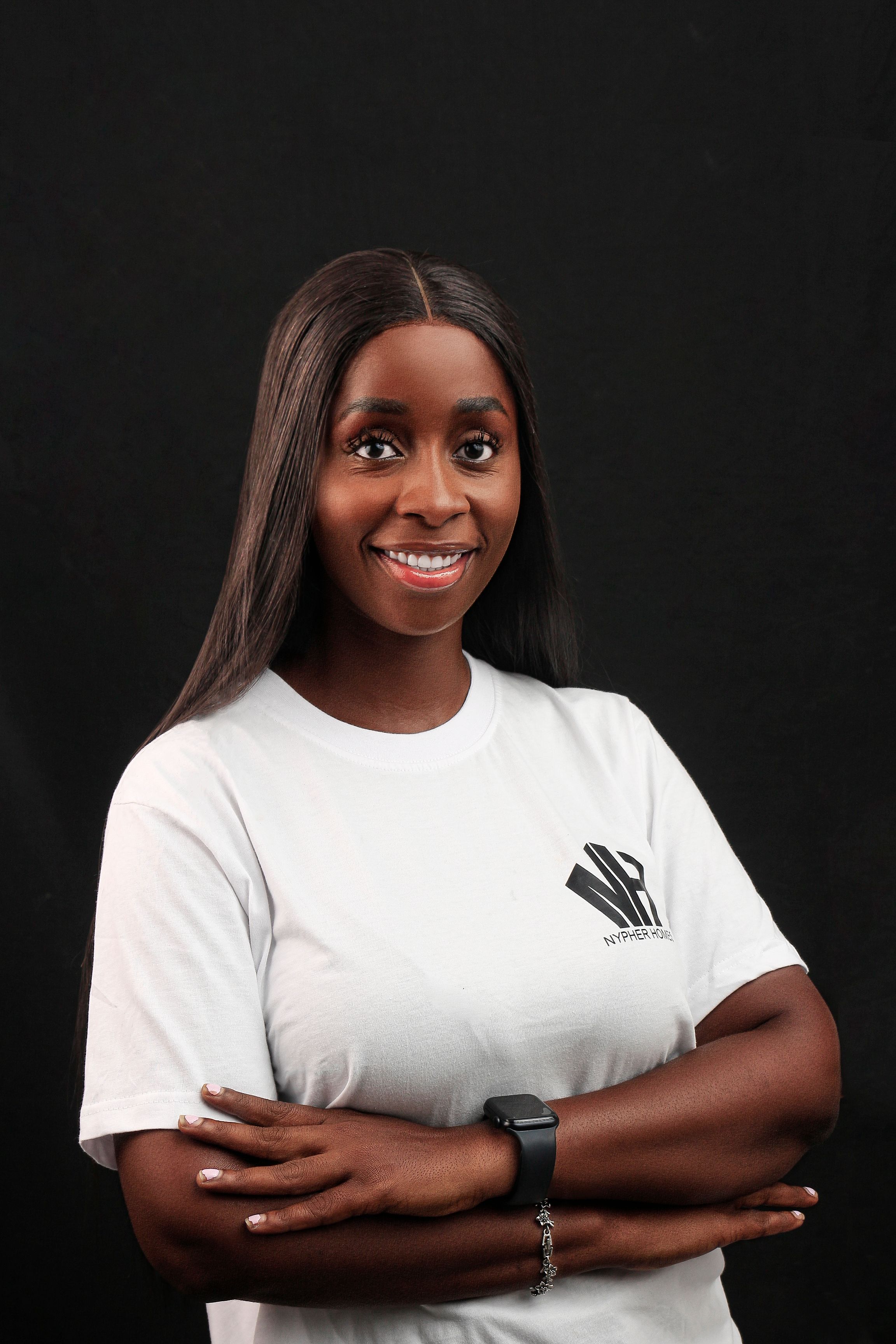 Confident young woman in a white shirt smiling in a studio portrait.