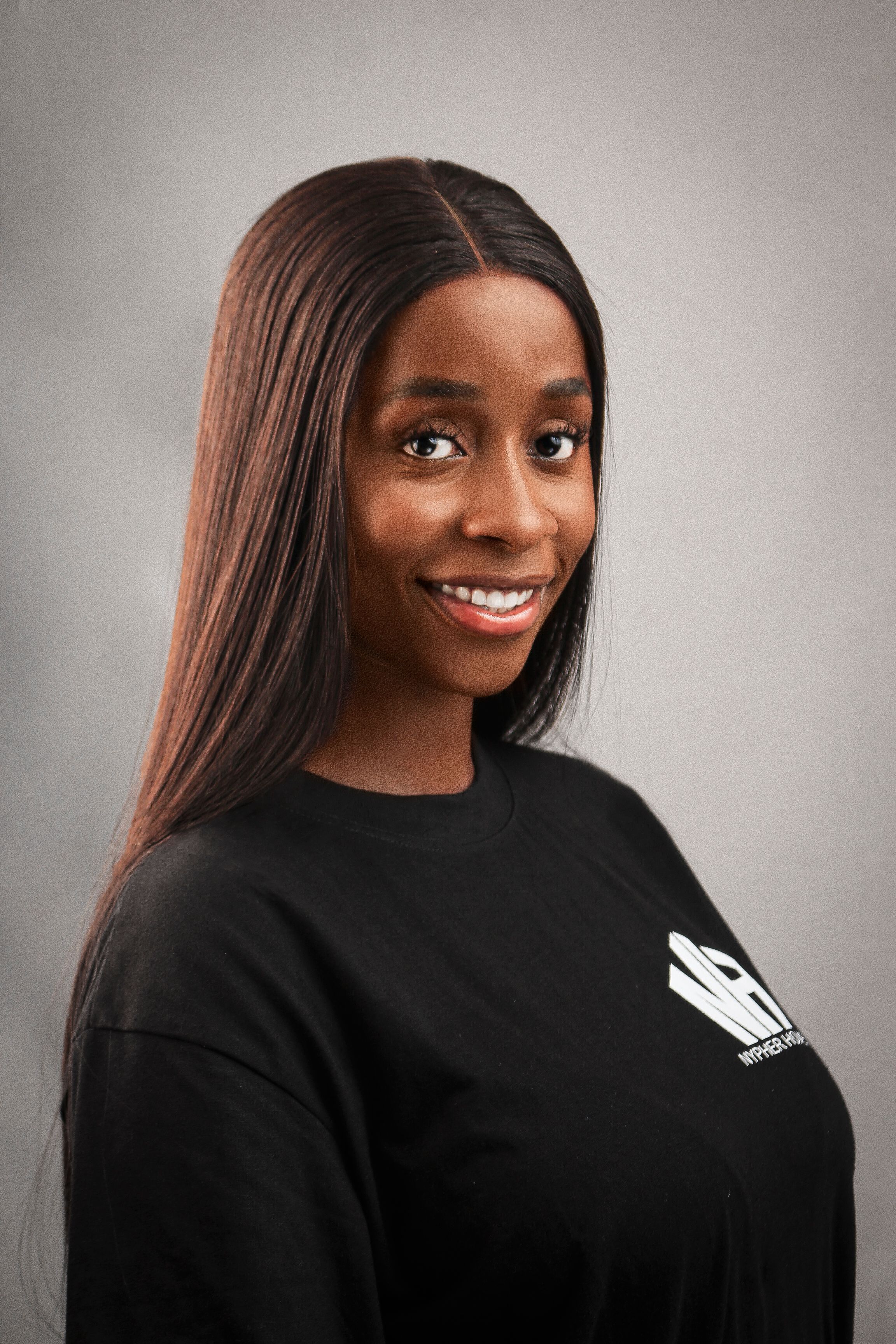 A friendly portrait of a young woman in casual wear, smiling confidently.