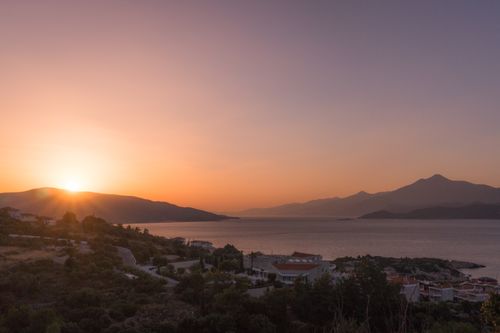 Free Stunning sunset view over a tranquil seaside village with mountains in the background, capturing the essence of nature's beauty. Stock Photo