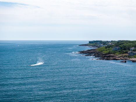 Captivating coastal view of Ogunquit, Maine, showcasing blue ocean waters, rocky shoreline, and a distant jet ski.