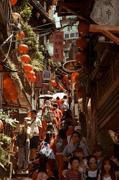 A bustling street filled with people and red Chinese lanterns during a daytime festival.