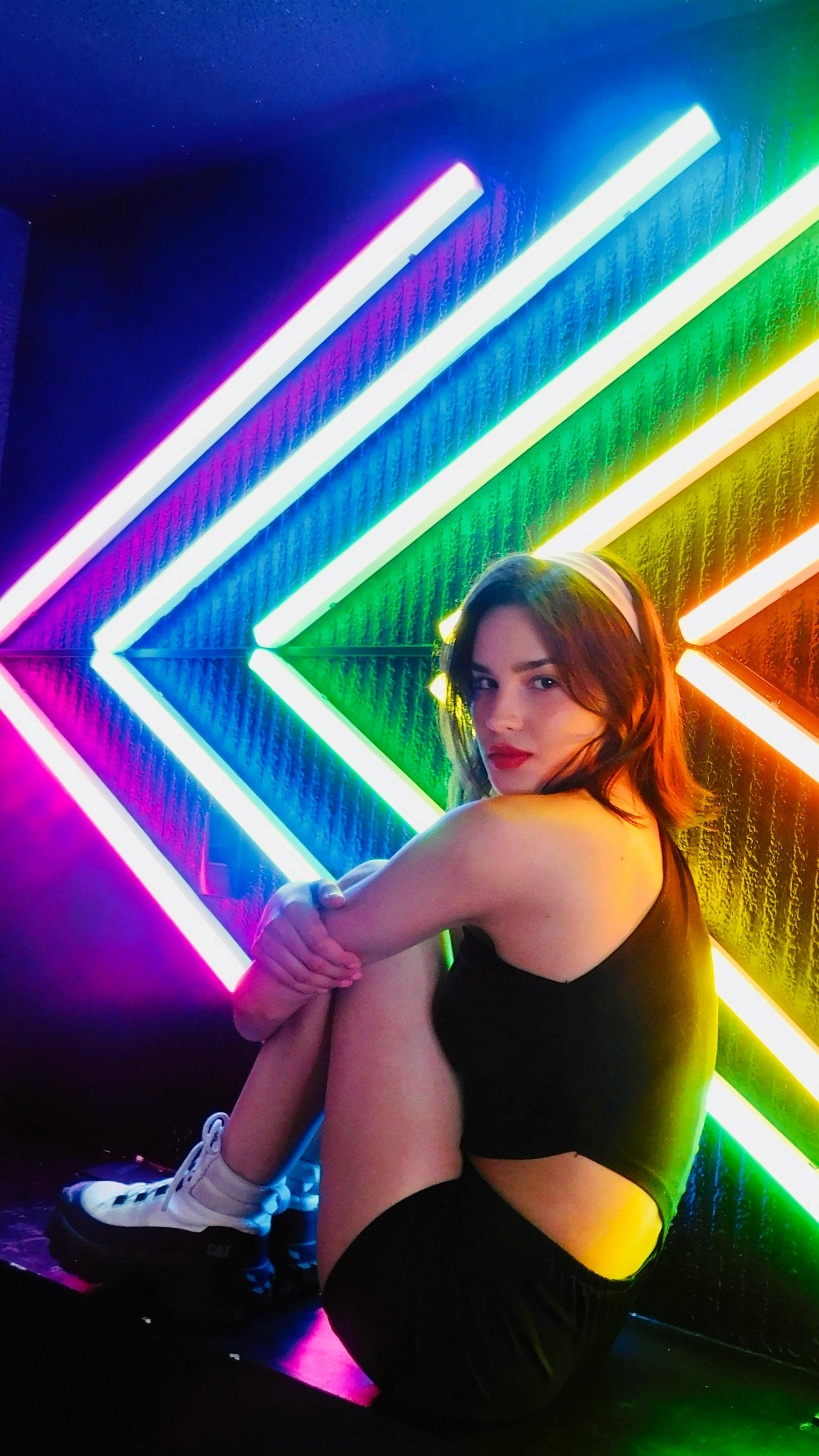 Captivating nightclub scene featuring a woman surrounded by colorful neon lights, exuding vibrant energy.