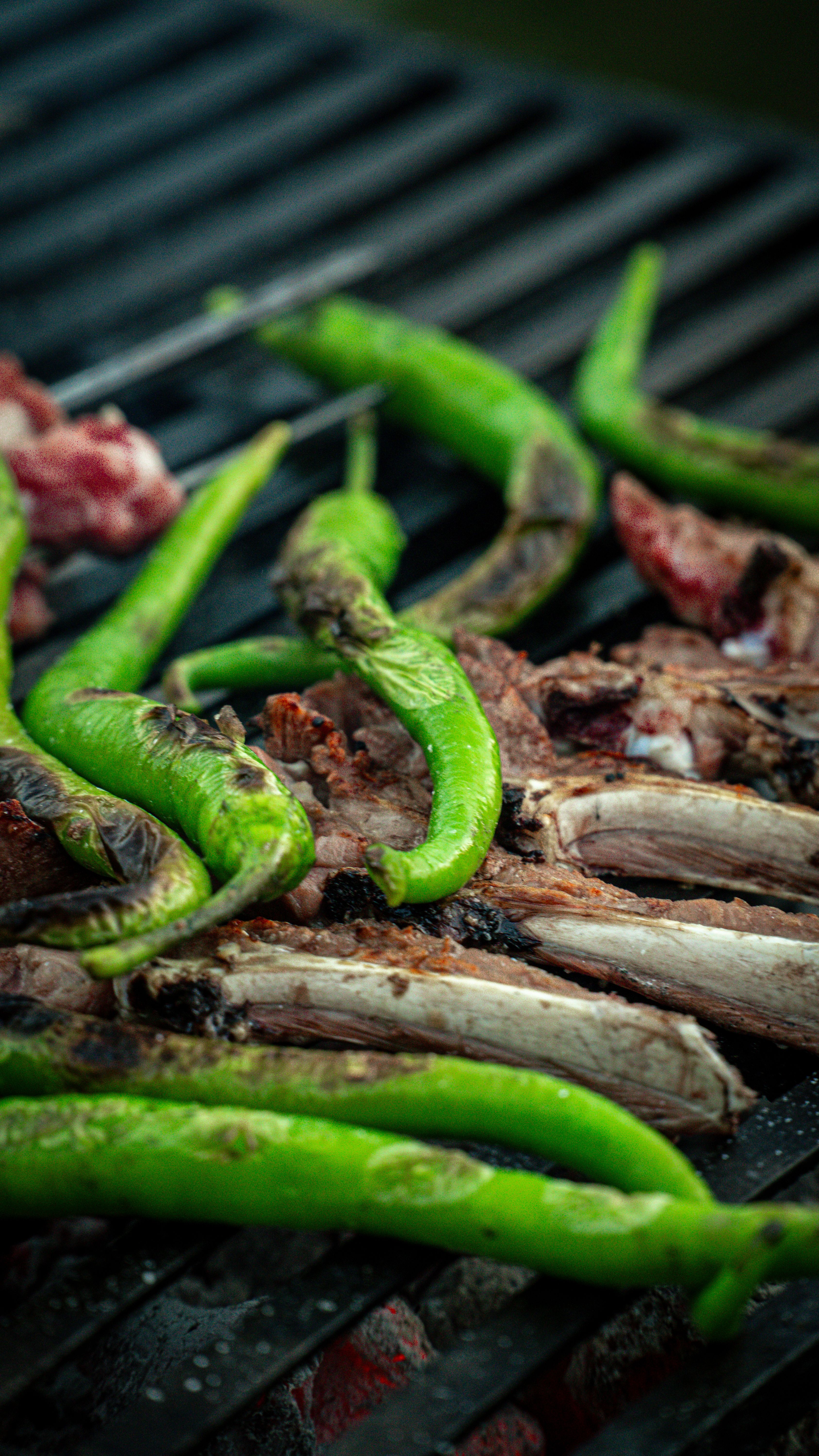 Fotomural Primer plano de pimientos verdes y carne asándose en una parrilla, enfatizando ingredientes frescos y cocina al aire libre.