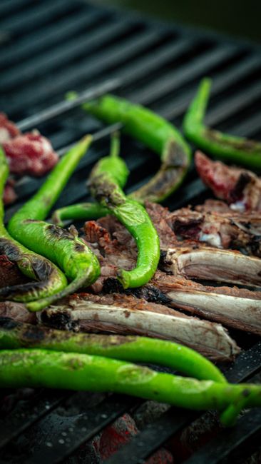 Fotomural Primer plano de pimientos verdes y carne asándose en una parrilla, enfatizando ingredientes frescos y cocina al aire libre.