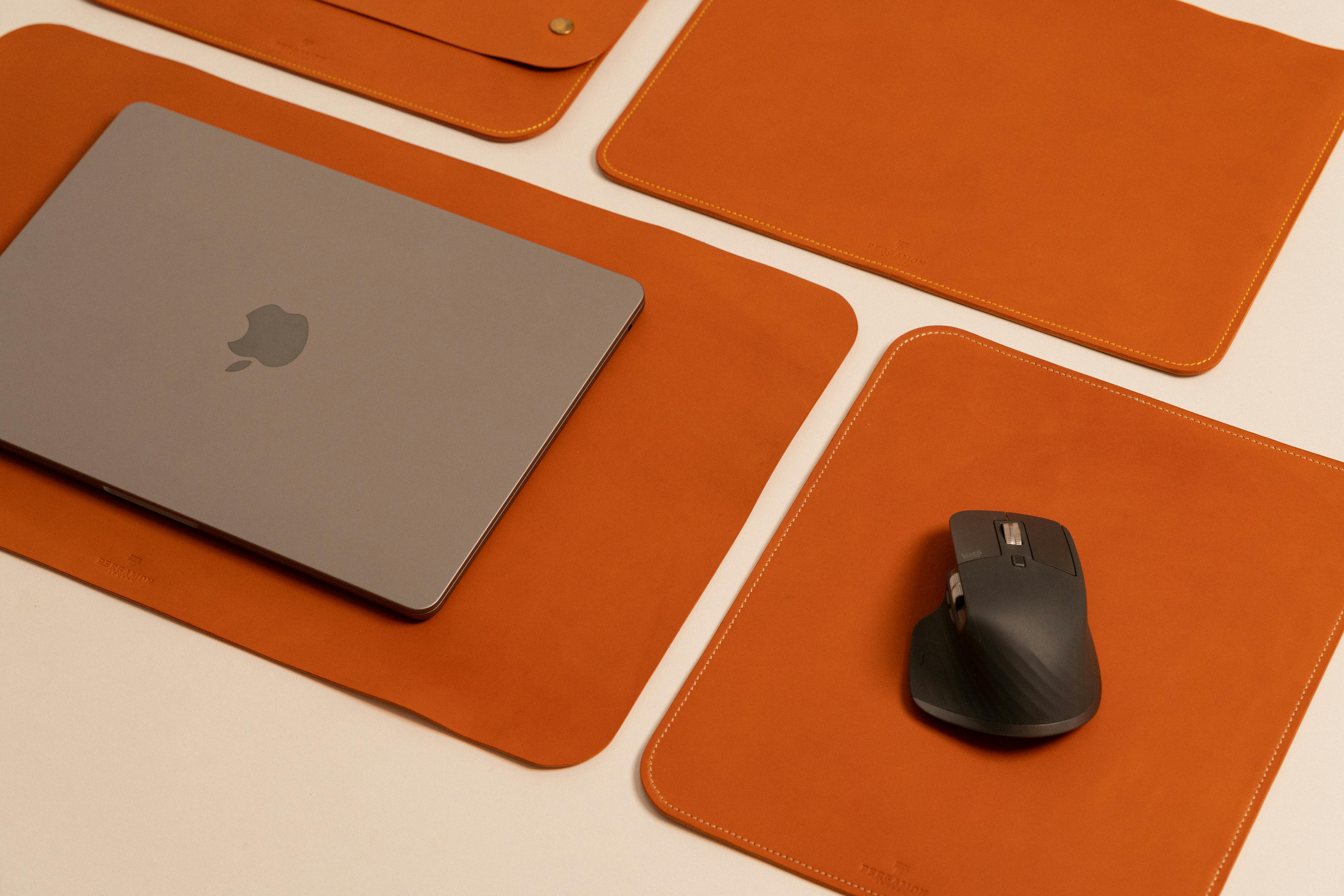 Stylish desktop featuring a laptop and mouse on leather pads, showcasing modern work essentials.