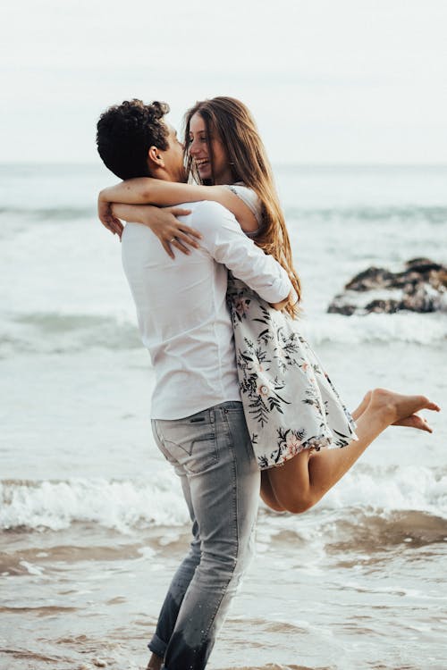 Free Photo of a Man Lifting Woman Near Body of Water Stock Photo