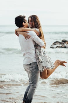 photo of a man lifting woman near body of water