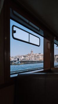 Scenic view of Istanbul across the Bosphorus, captured from a ferry window, showcasing the city's skyline.
