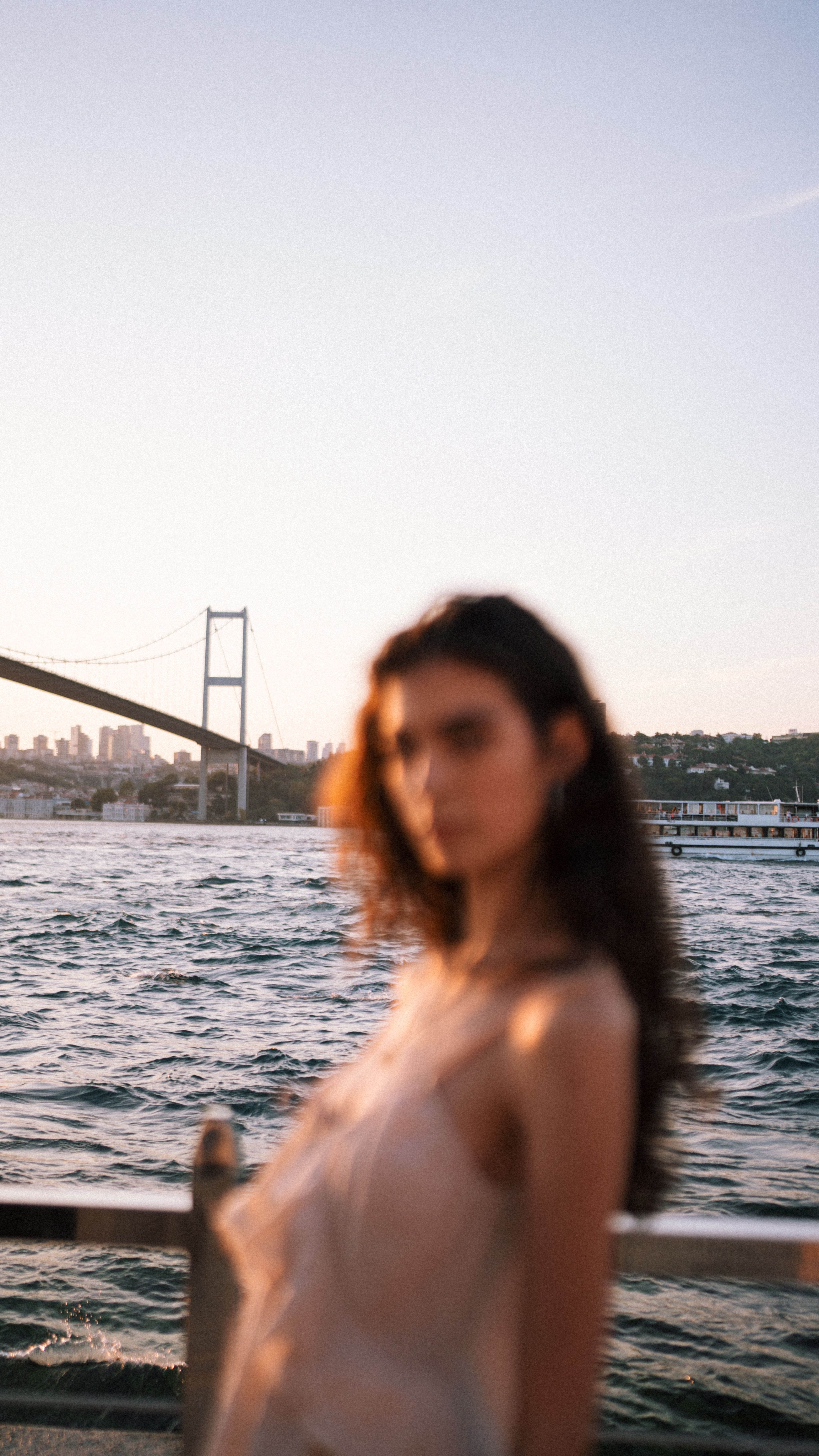 Artistic blur of a woman near Bosphorus Bridge at sunset, capturing serene beauty.