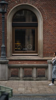Street view of a brick building with a passing woman, urban aesthetic.