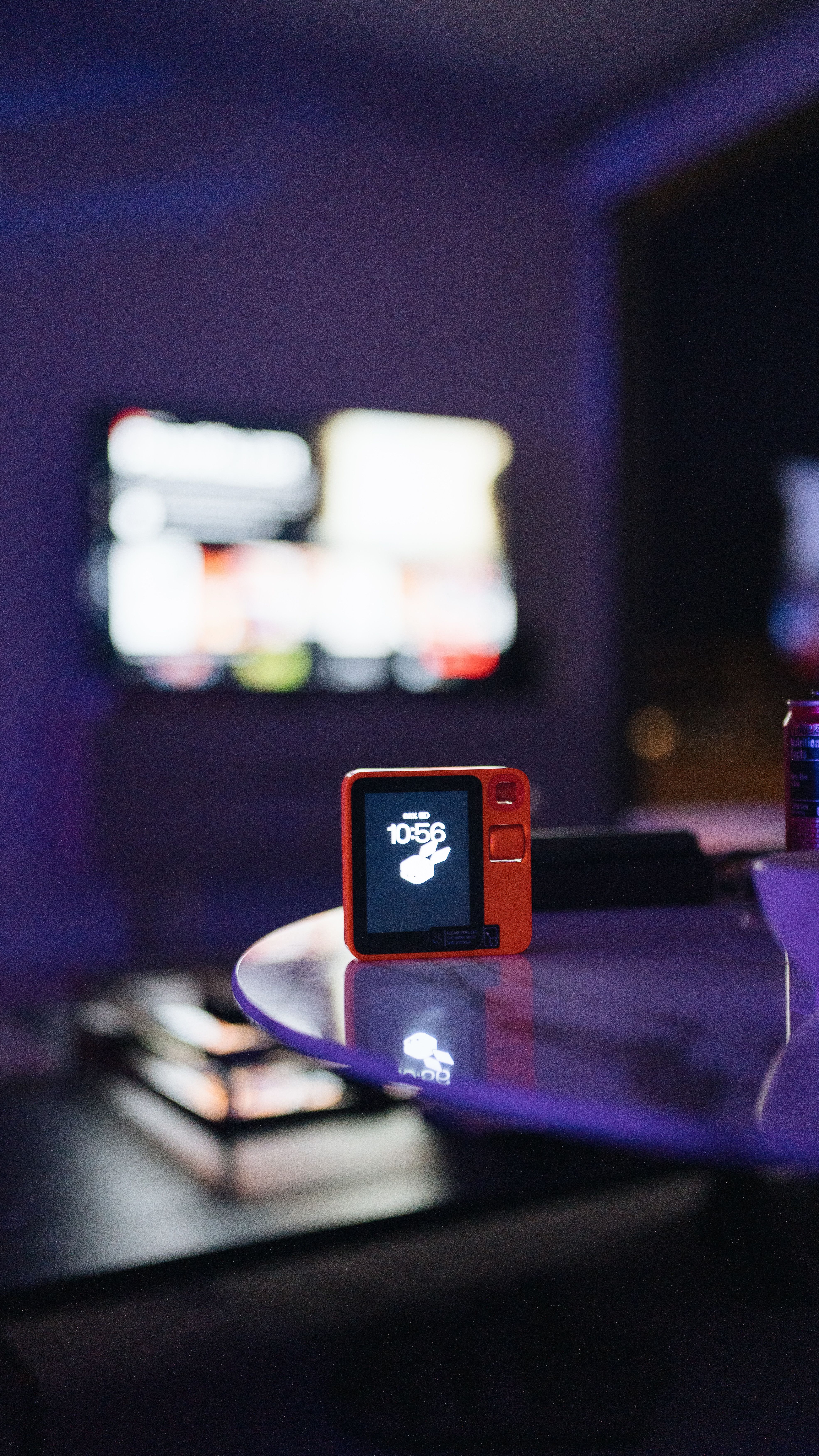 A digital device on a glass table in a neon-lit modern indoor setting.