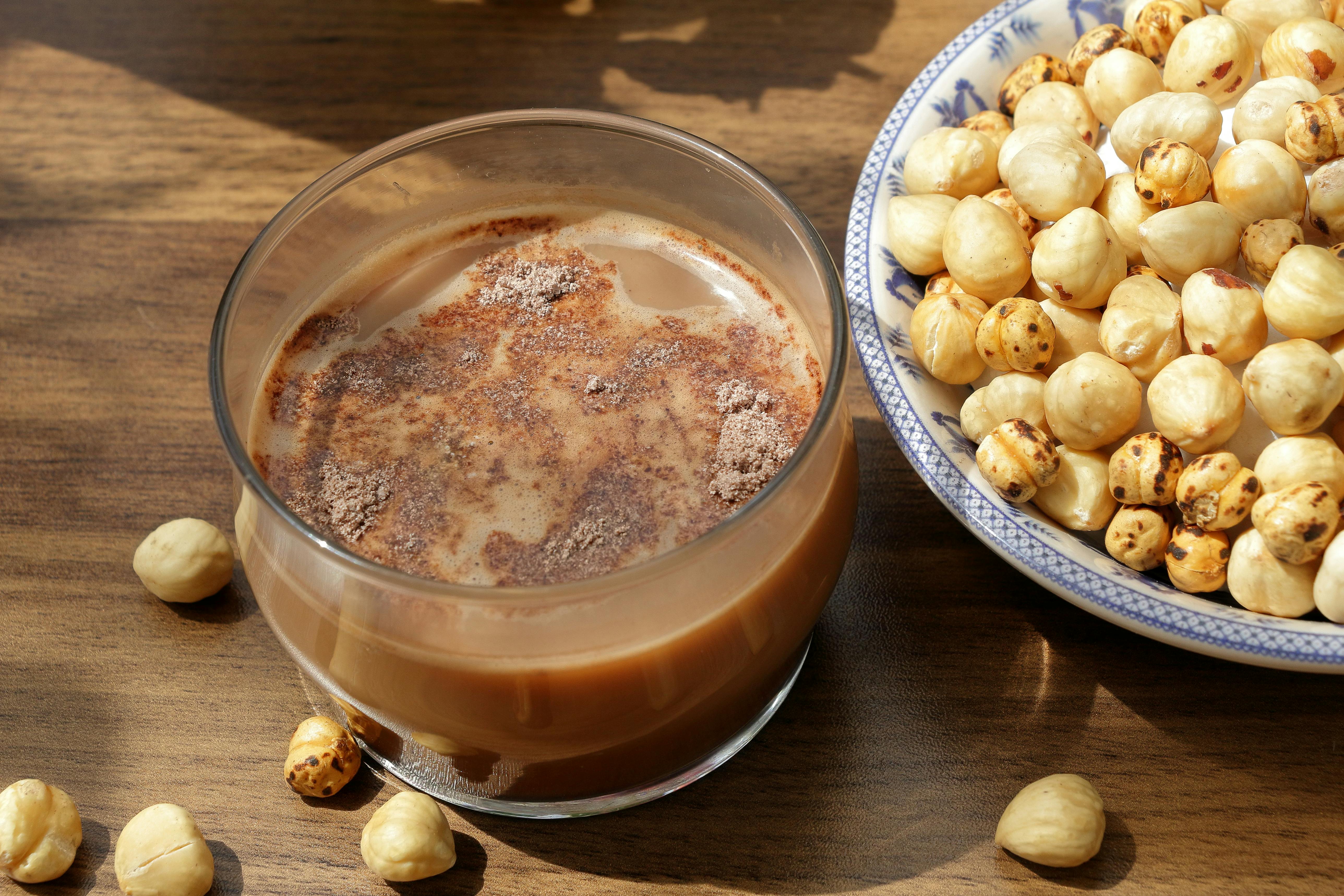 A glass of milk and nuts on a table