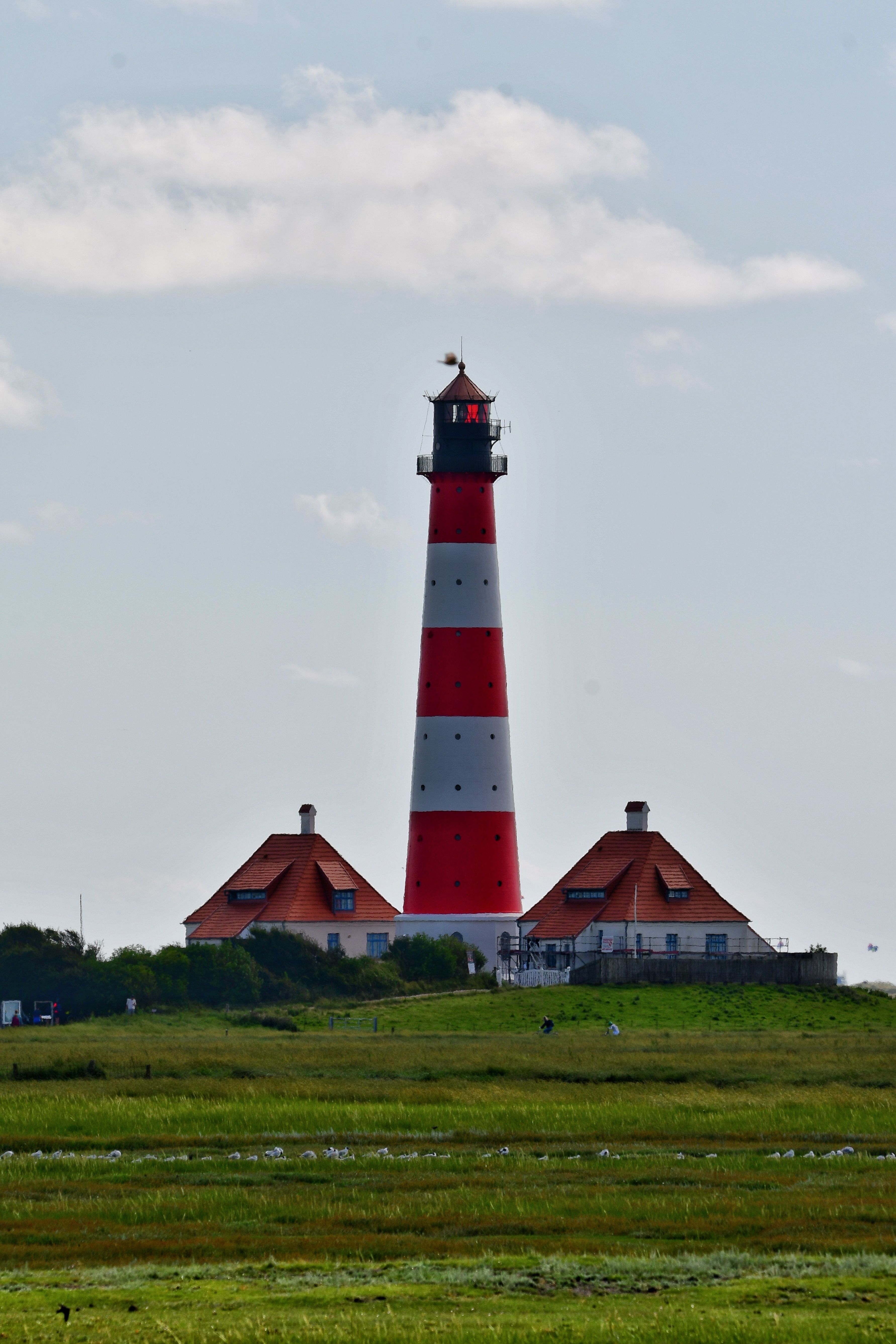 A red and white lighthouse sitting on top of a grassy field · Free ...