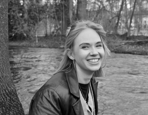 Free Young woman smiling cheerfully by a river in Munich, Germany. Stock Photo