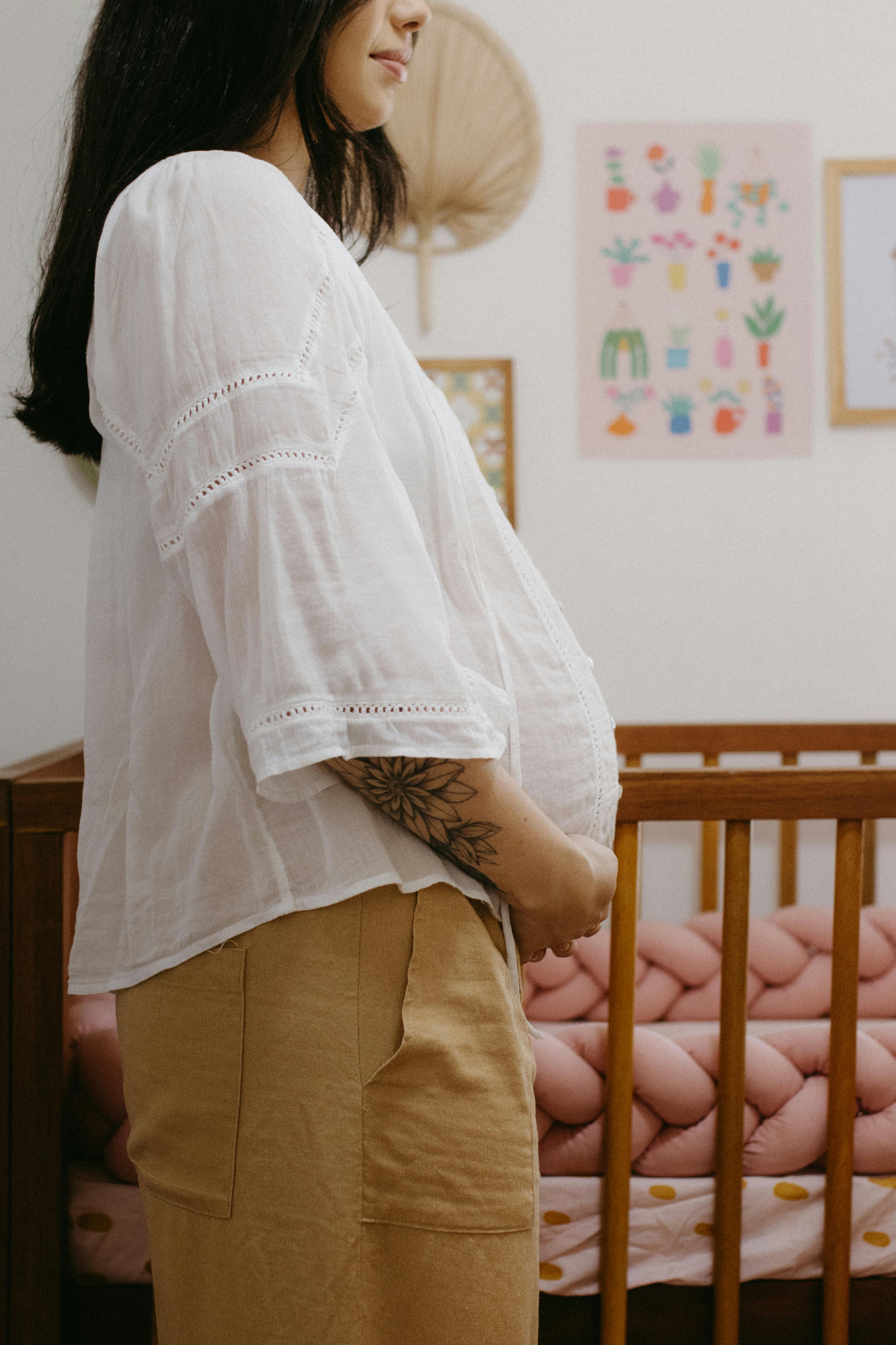 a pregnant woman standing in front of a crib