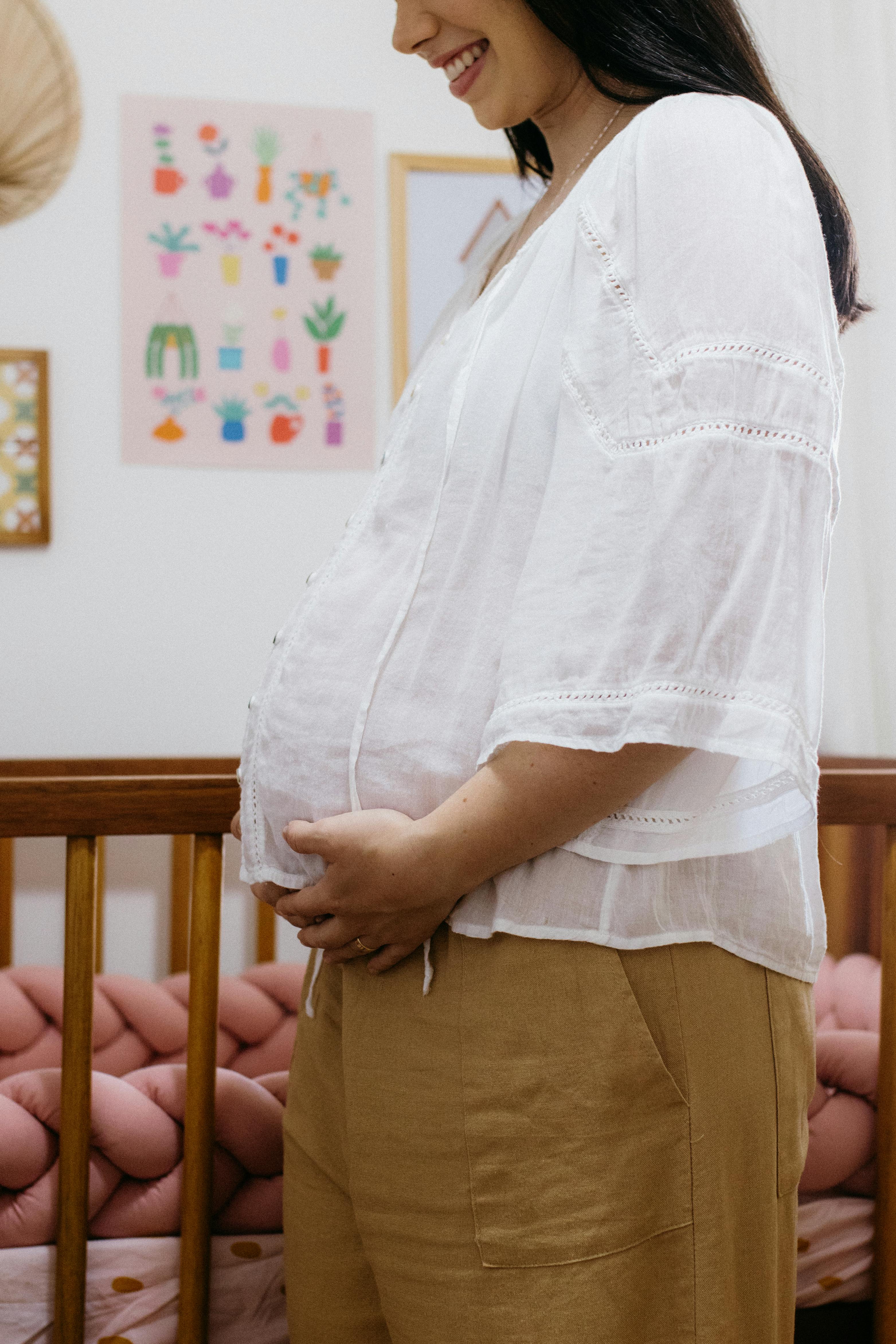 a pregnant woman stands in her bedroom