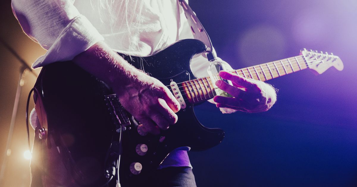 Close-up of a musician passionately playing an electric guitar under stage lights.