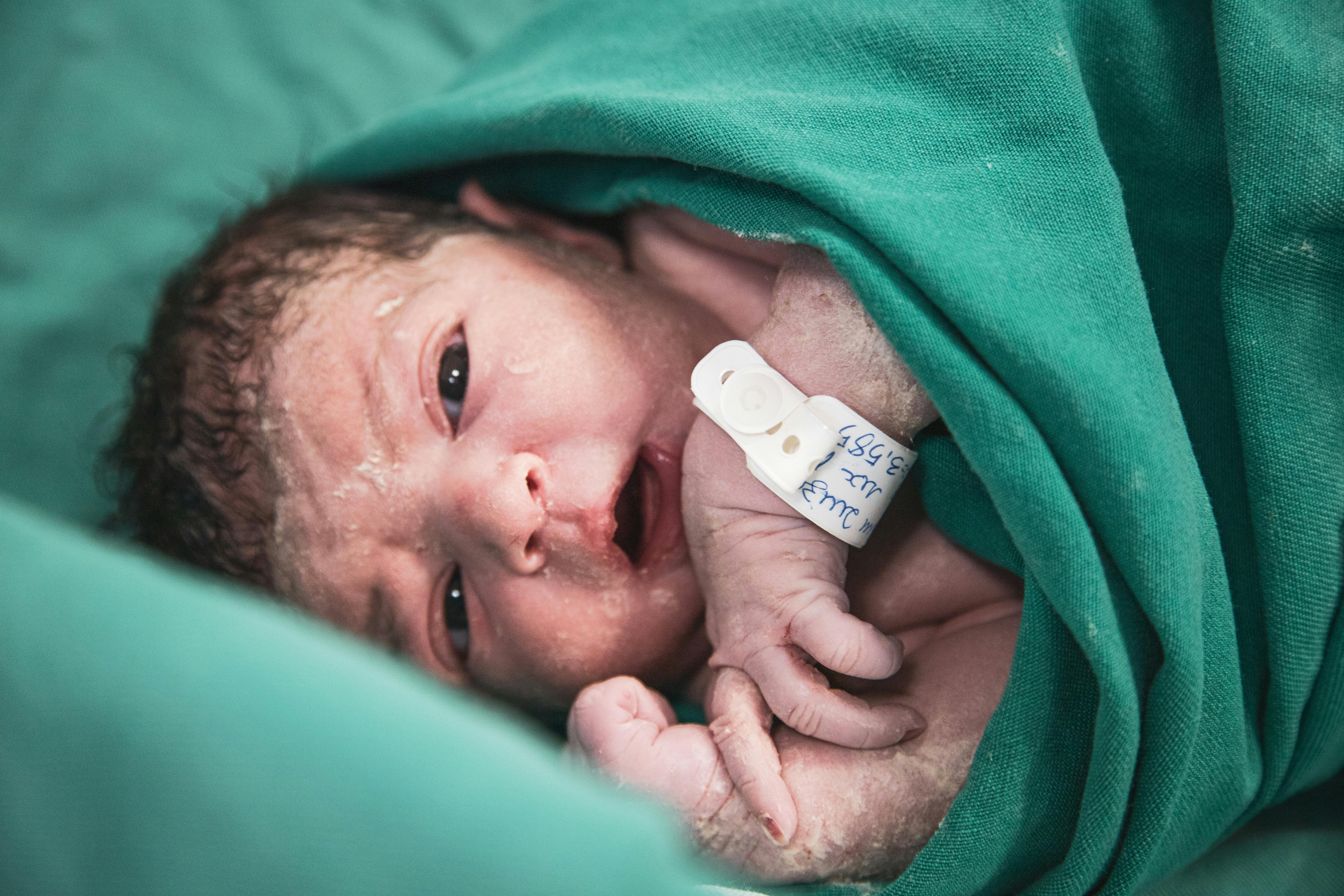 a newborn wrapped in green blanket with a green blanket