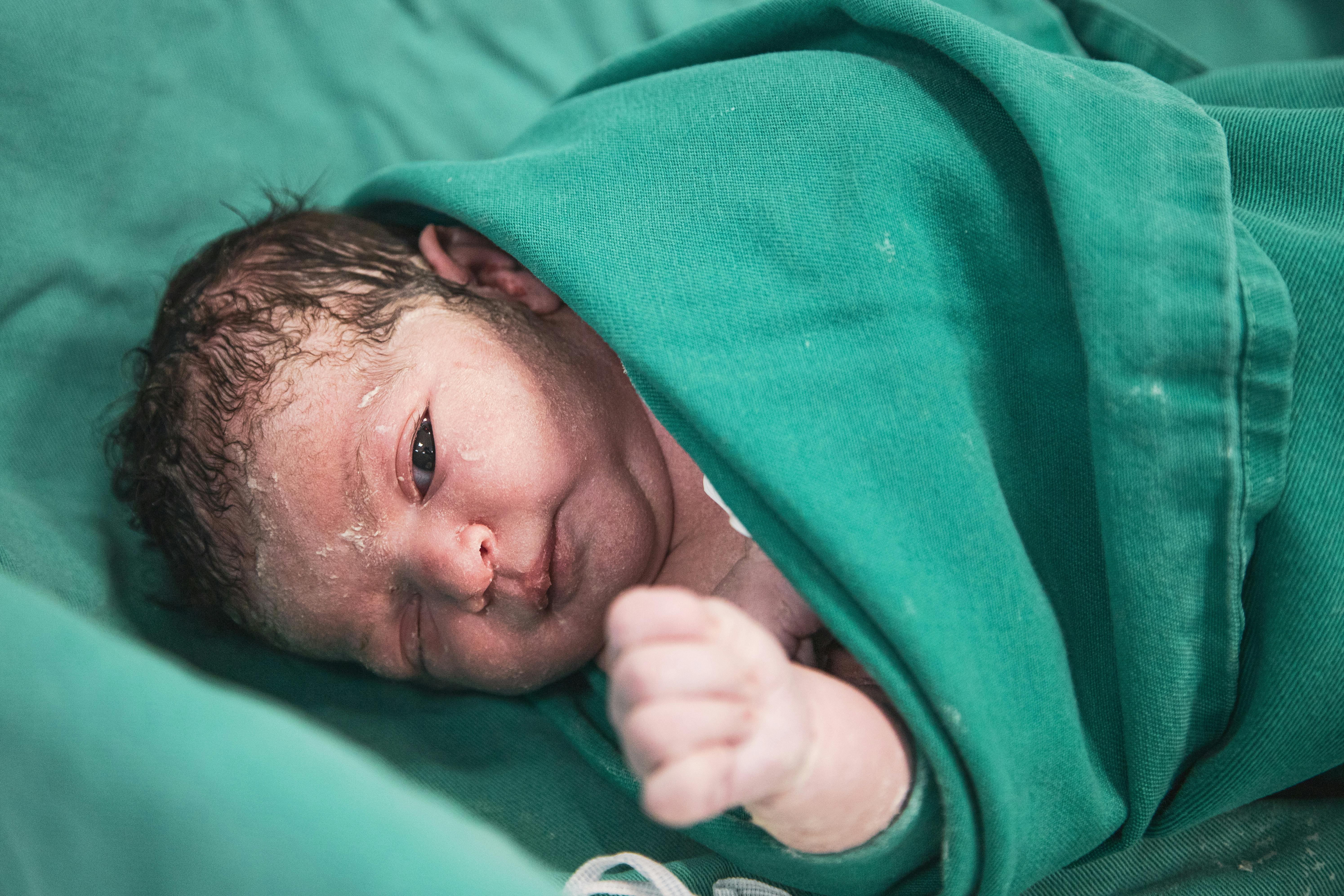 a newborn baby wrapped in green blanket