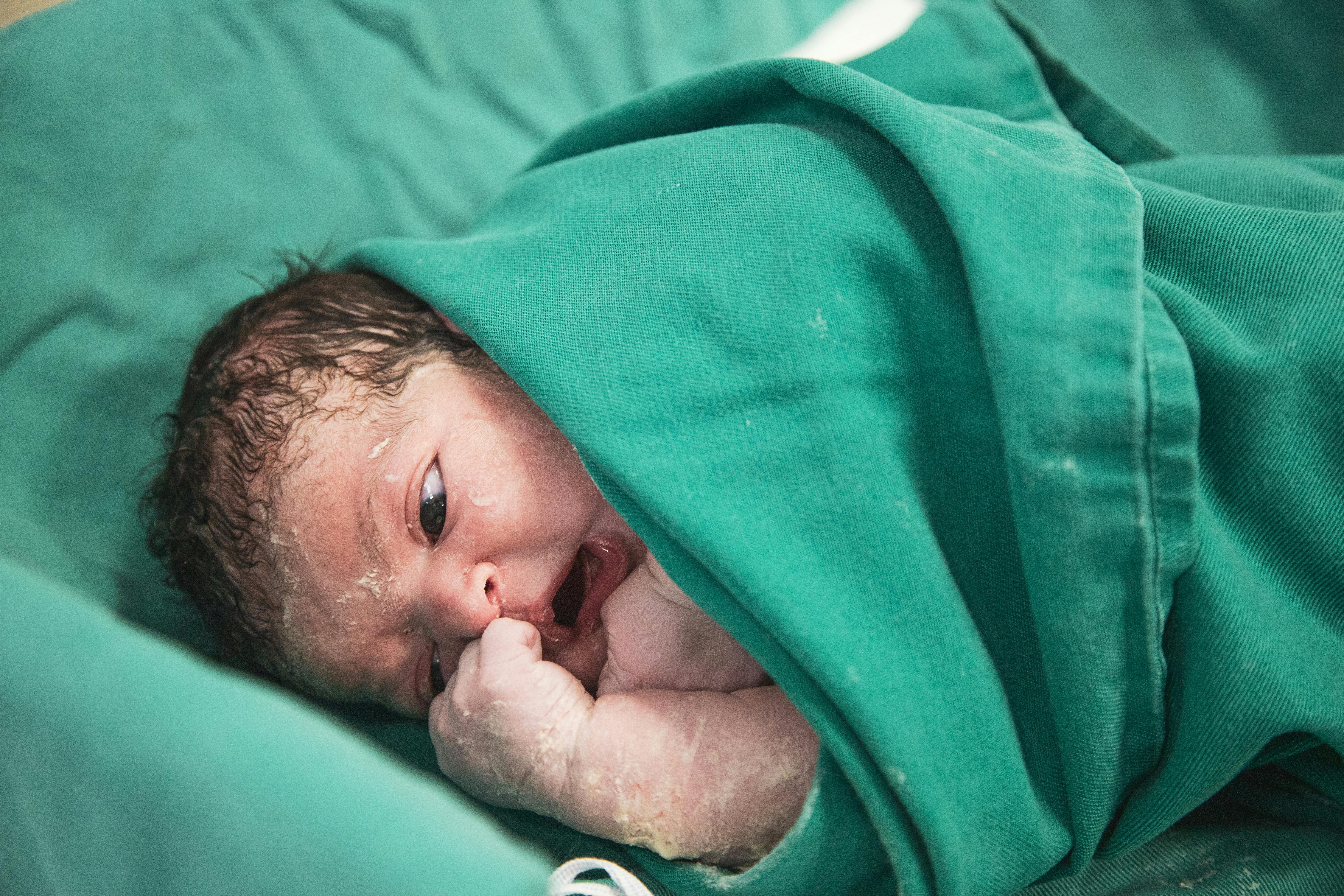 a newborn baby wrapped in green blanket