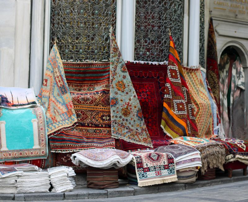 Vibrant Turkish carpets on display outside a traditional bazaar, showcasing rich patterns and culture.