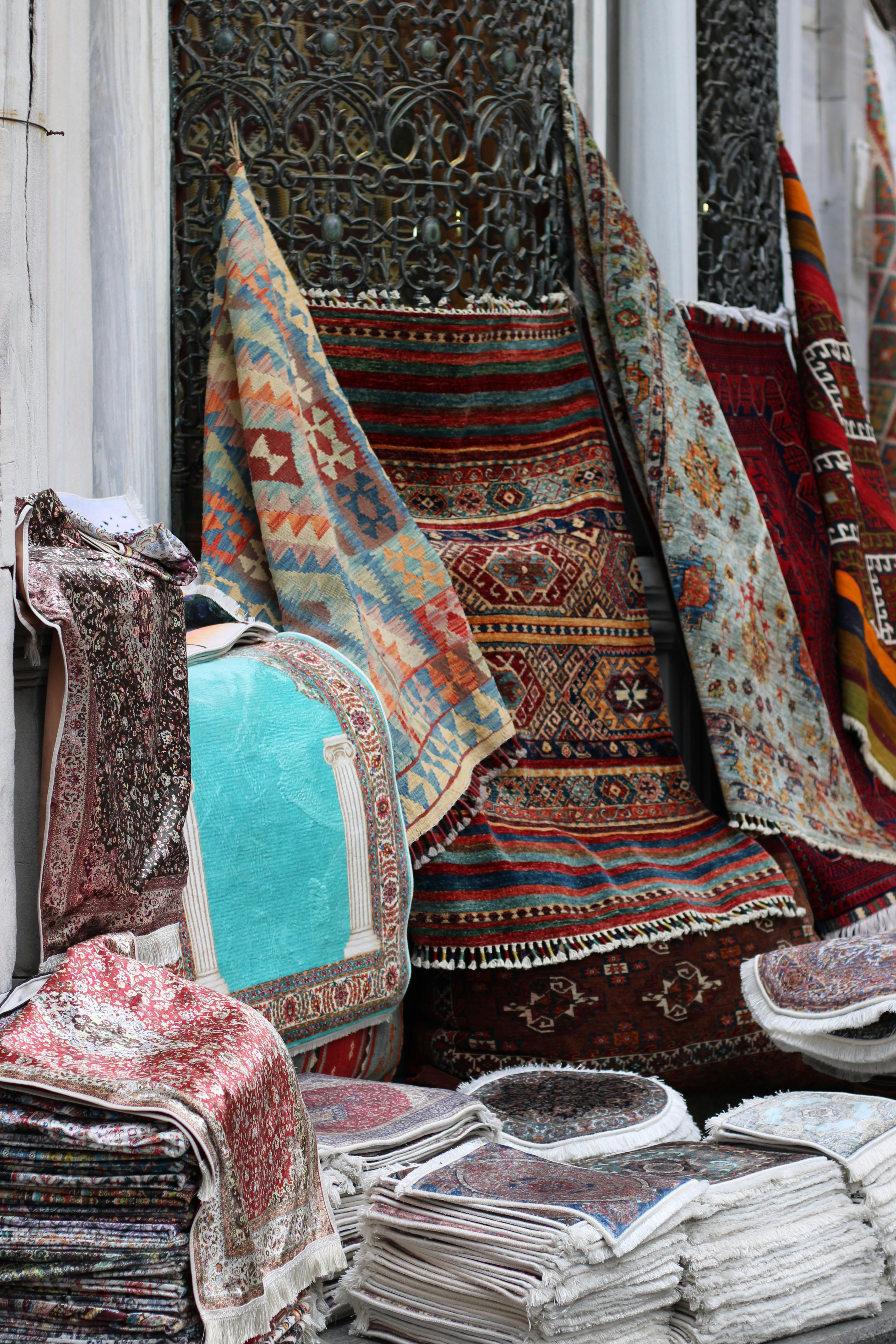 a pile of rugs on a sidewalk in a city