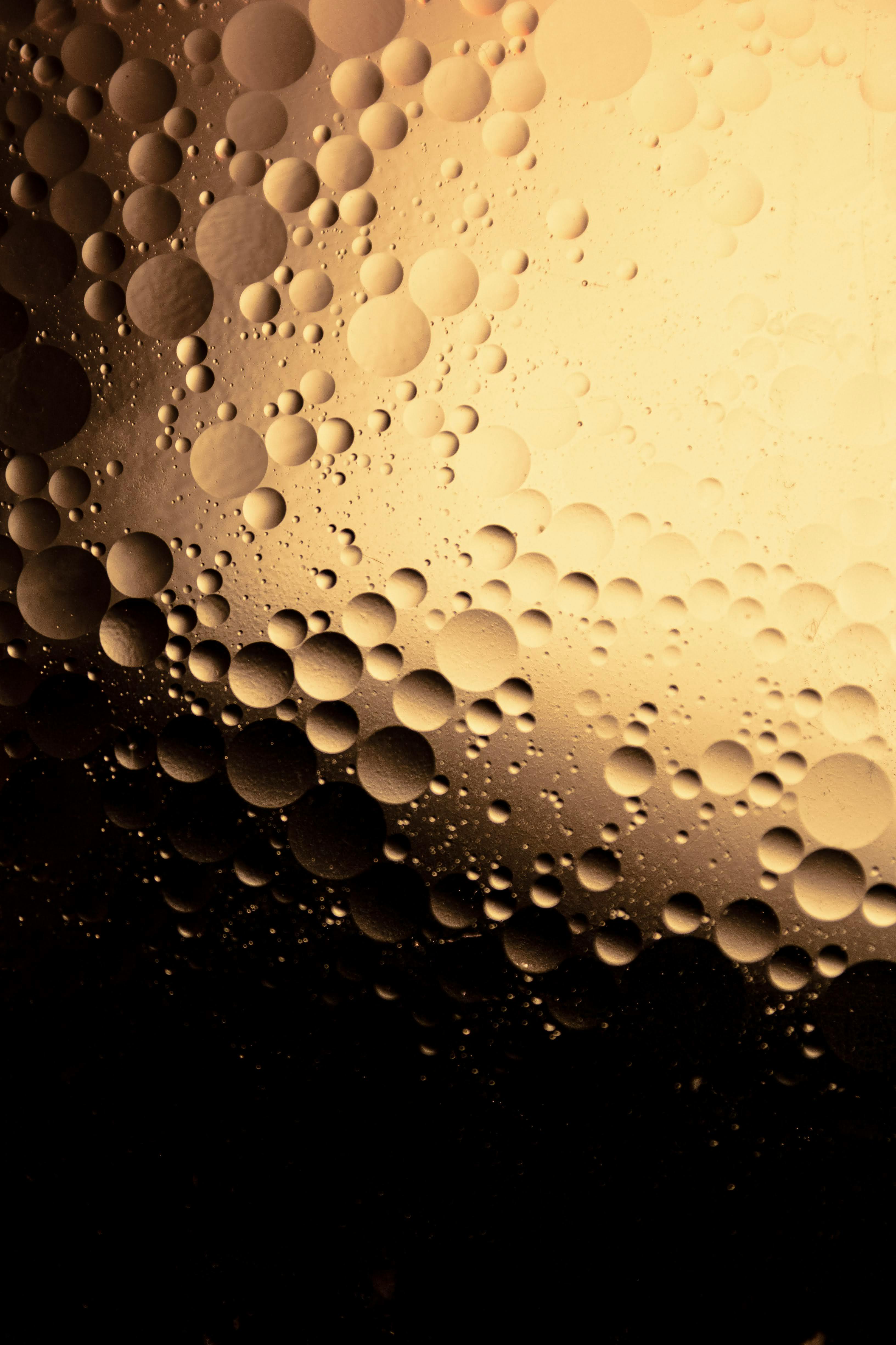 Captivating abstract art of golden bubbles in oil and water mix, creating a unique texture.