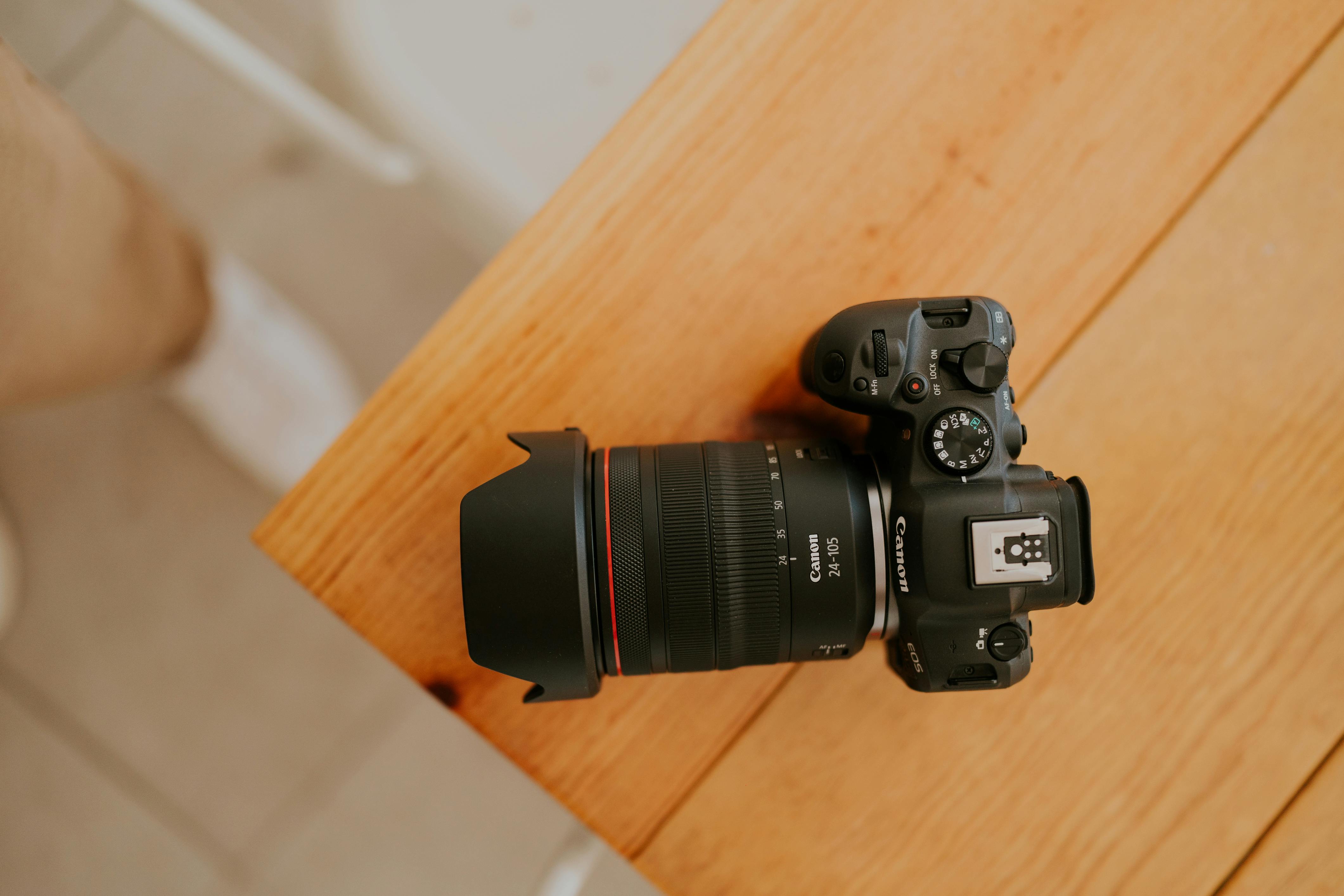 Free Close-up of a professional DSLR camera resting on a wooden table, highlighting photography equipment. Stock Photo