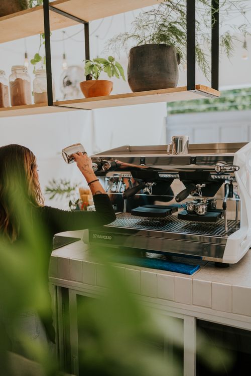 Free A skilled barista making coffee art at a trendy cafe with a modern espresso machine. Stock Photo
