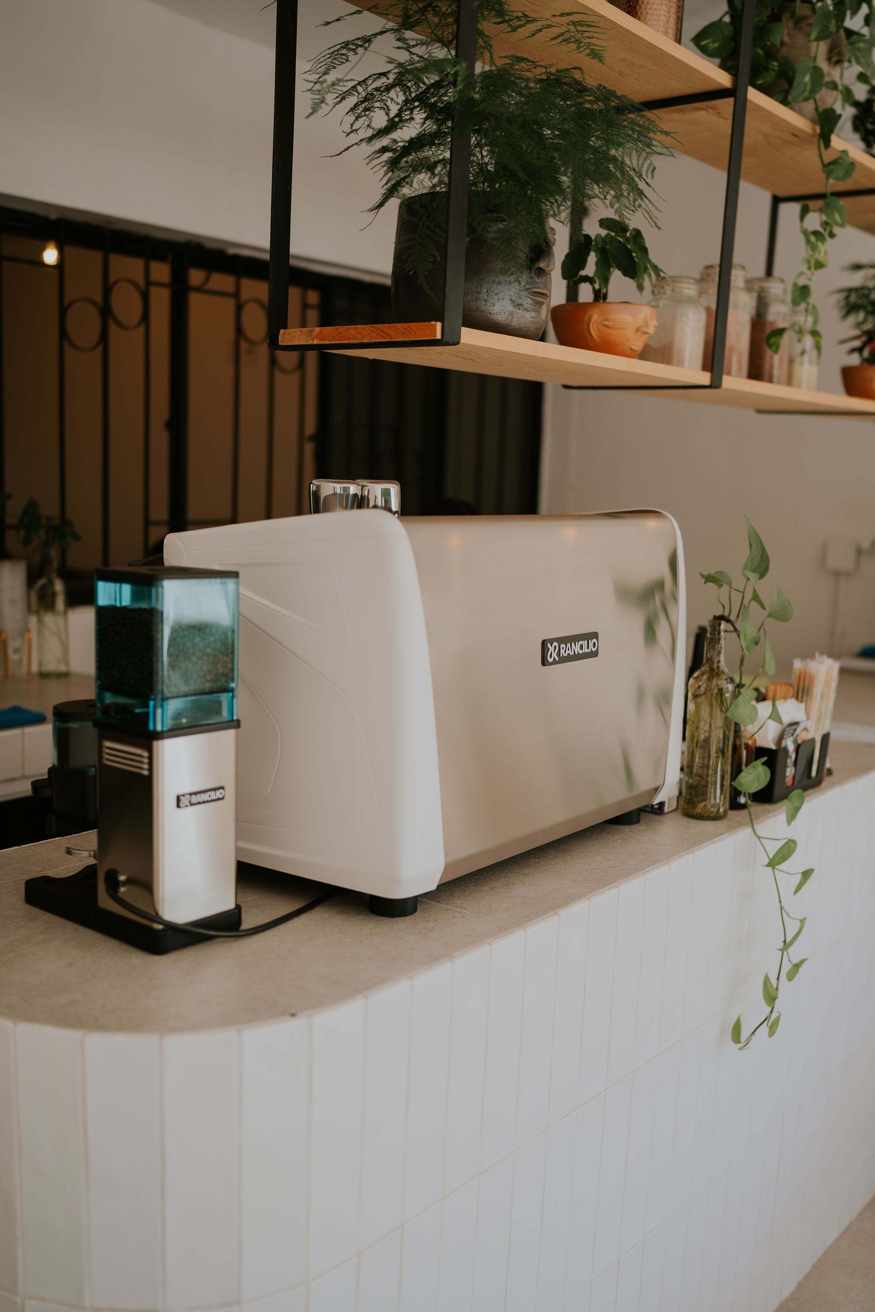 White floating shelf mounted above a coffee and tea bar holding mugs and storage canisters