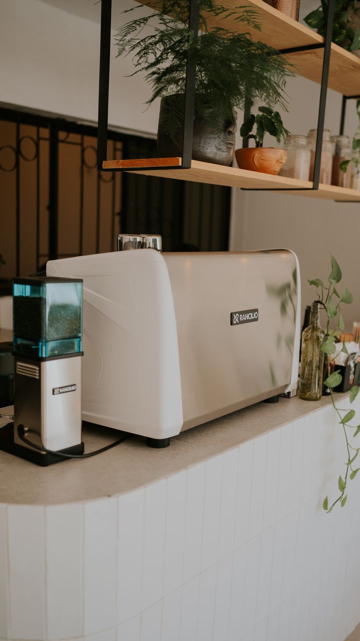 White floating shelf mounted above a coffee and tea bar holding mugs and storage canisters