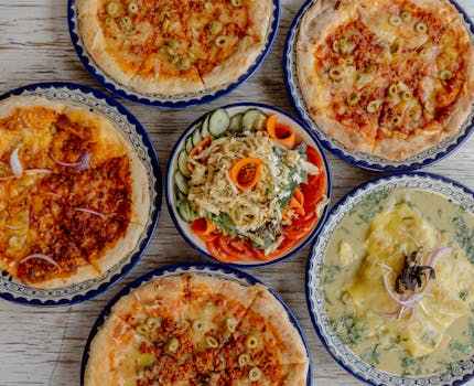A vibrant spread of pizzas and salads on a rustic table in Lerma, México.