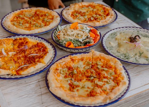 A delightful spread of various pizzas and a fresh salad on a rustic wooden table, perfect for a cozy meal.