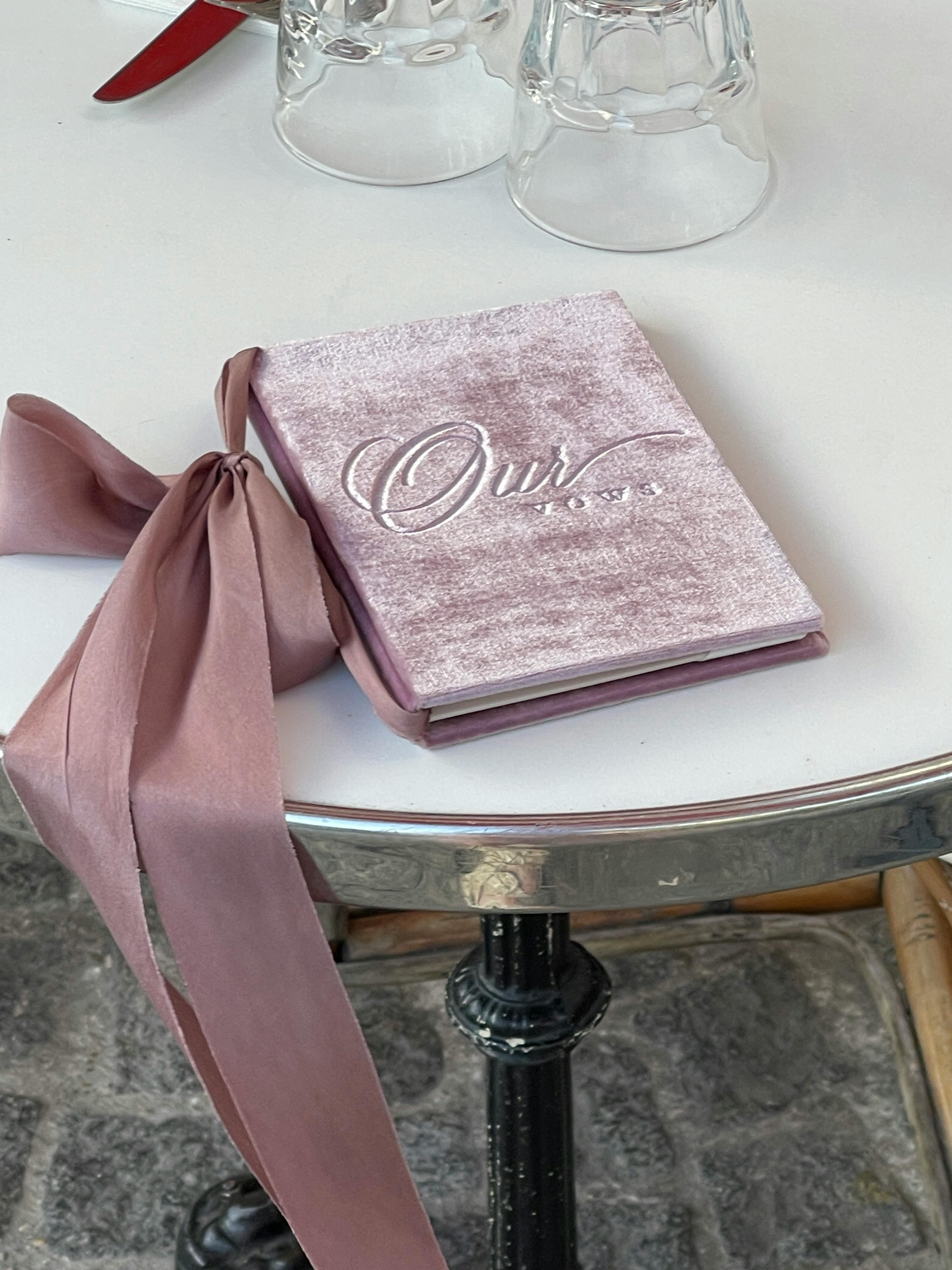 A stylish pink journal with ribbon on a white table, perfect for dining memories.