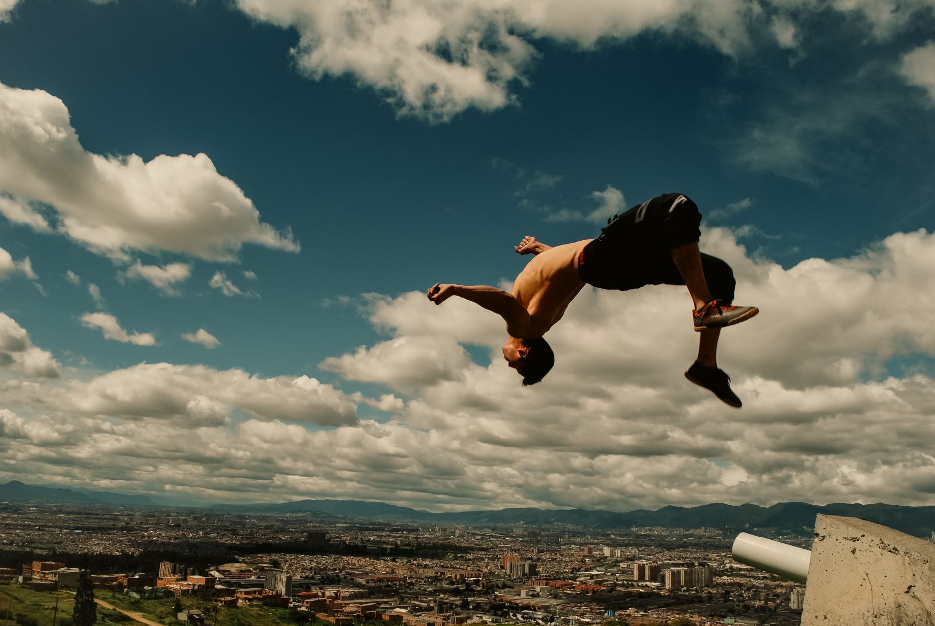 A man performs a daring parkour flip over Bogotá's skyline, capturing the spirit of freedom and adventure.
