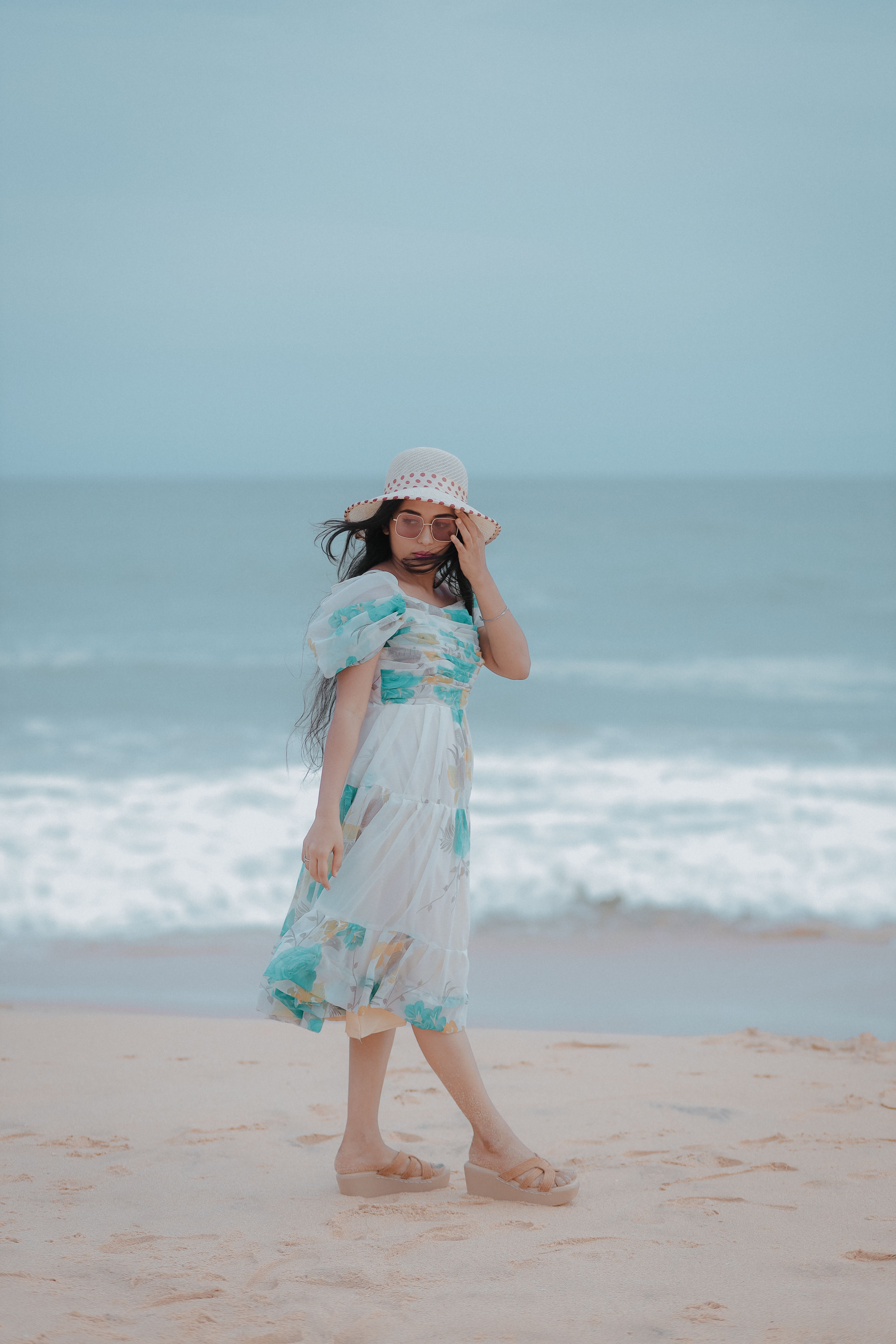 A woman in a dress and hat on the beach · Free Stock Photo