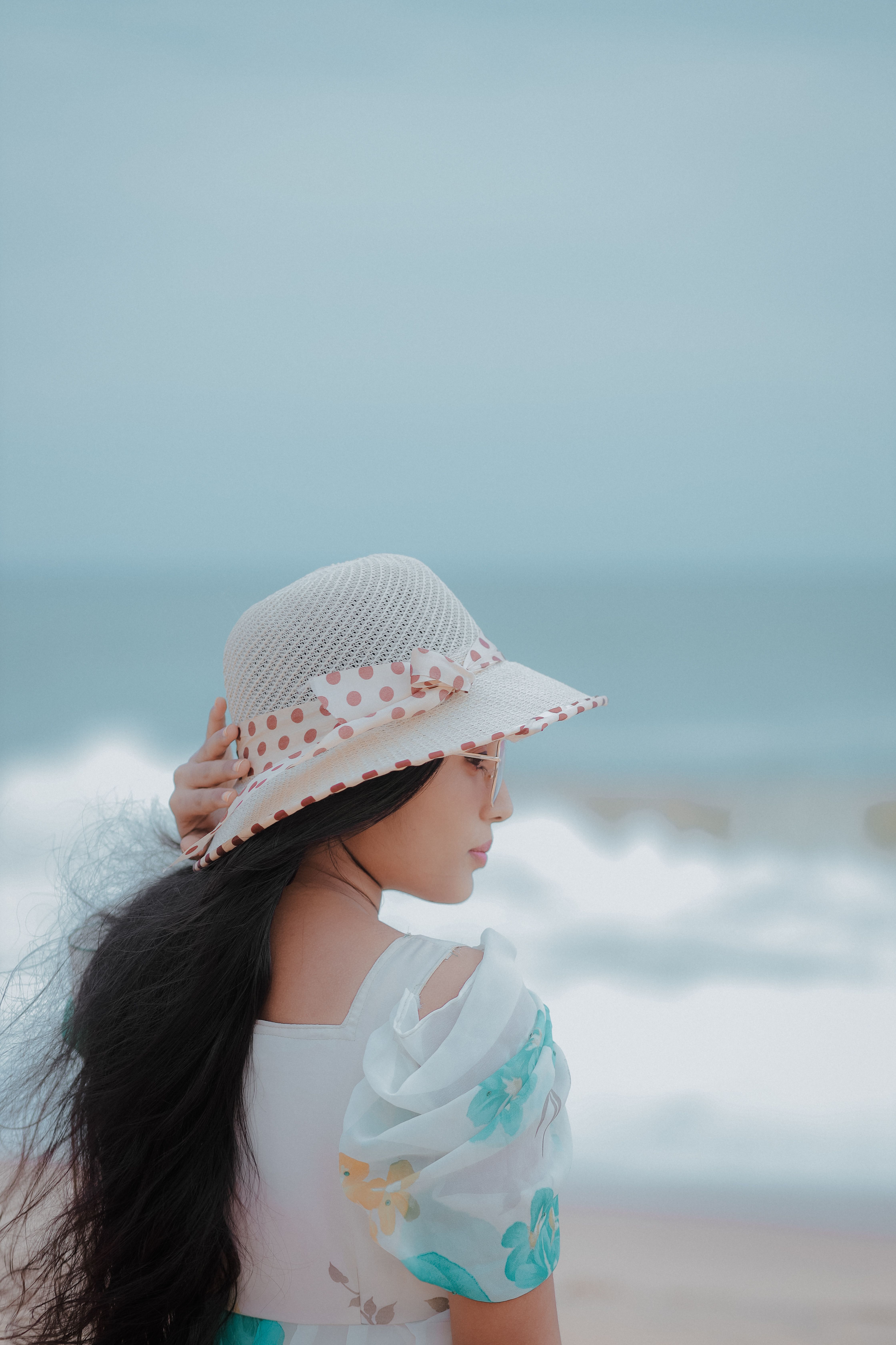 A woman in a dress and hat standing on the beach · Free Stock Photo
