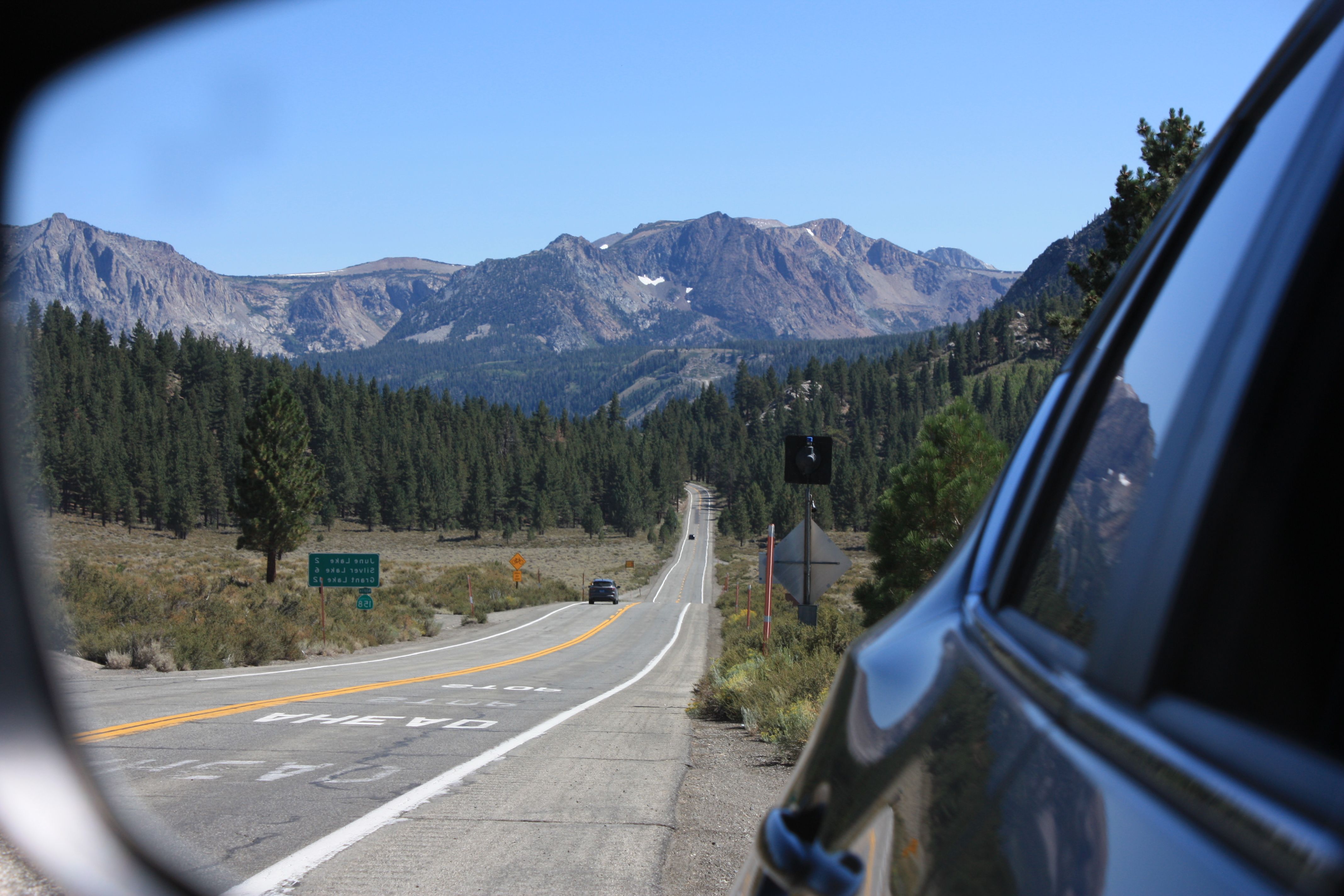 A car is driving down a road with mountains in the background · Free ...