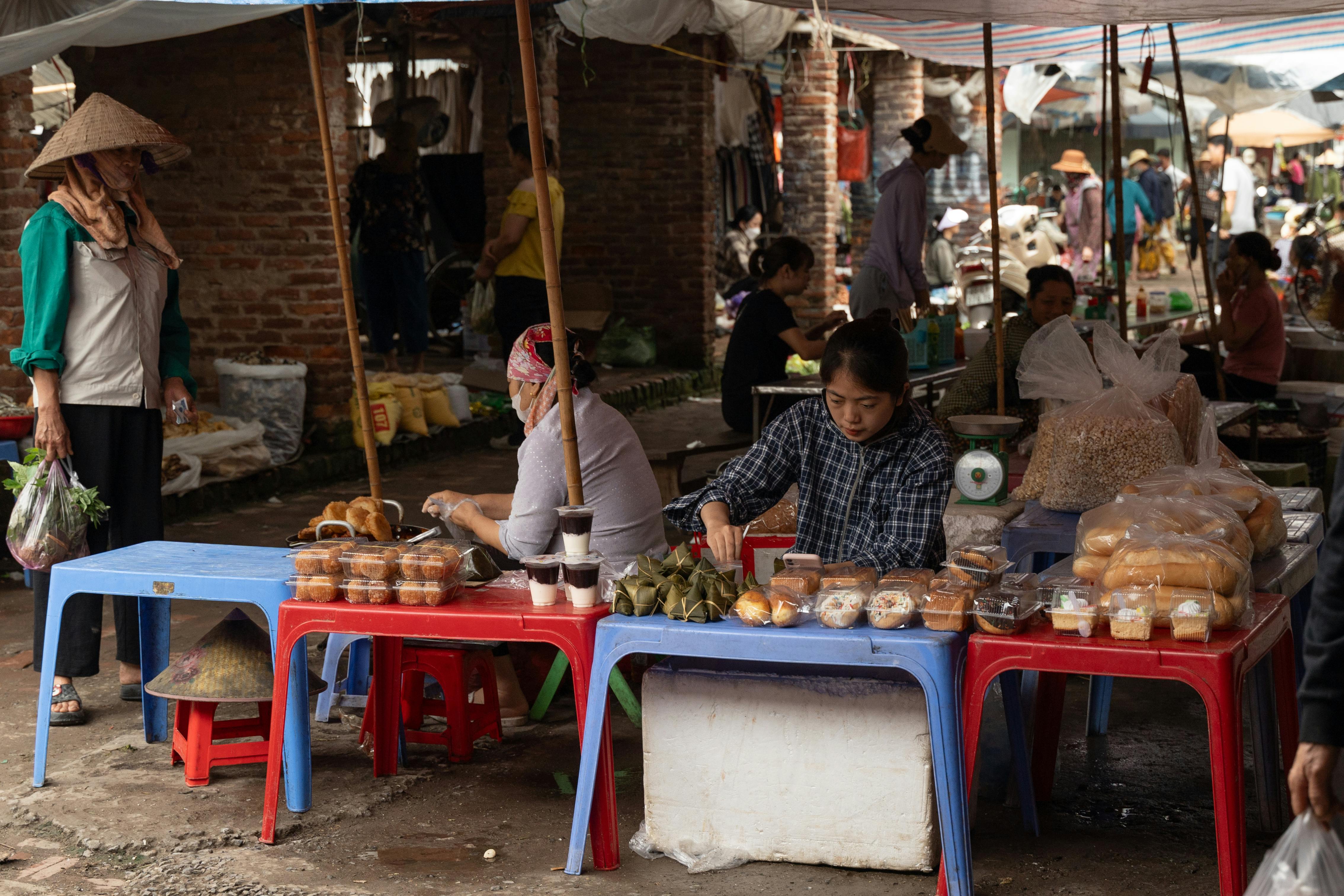 a woman is selling food at an outdoor market