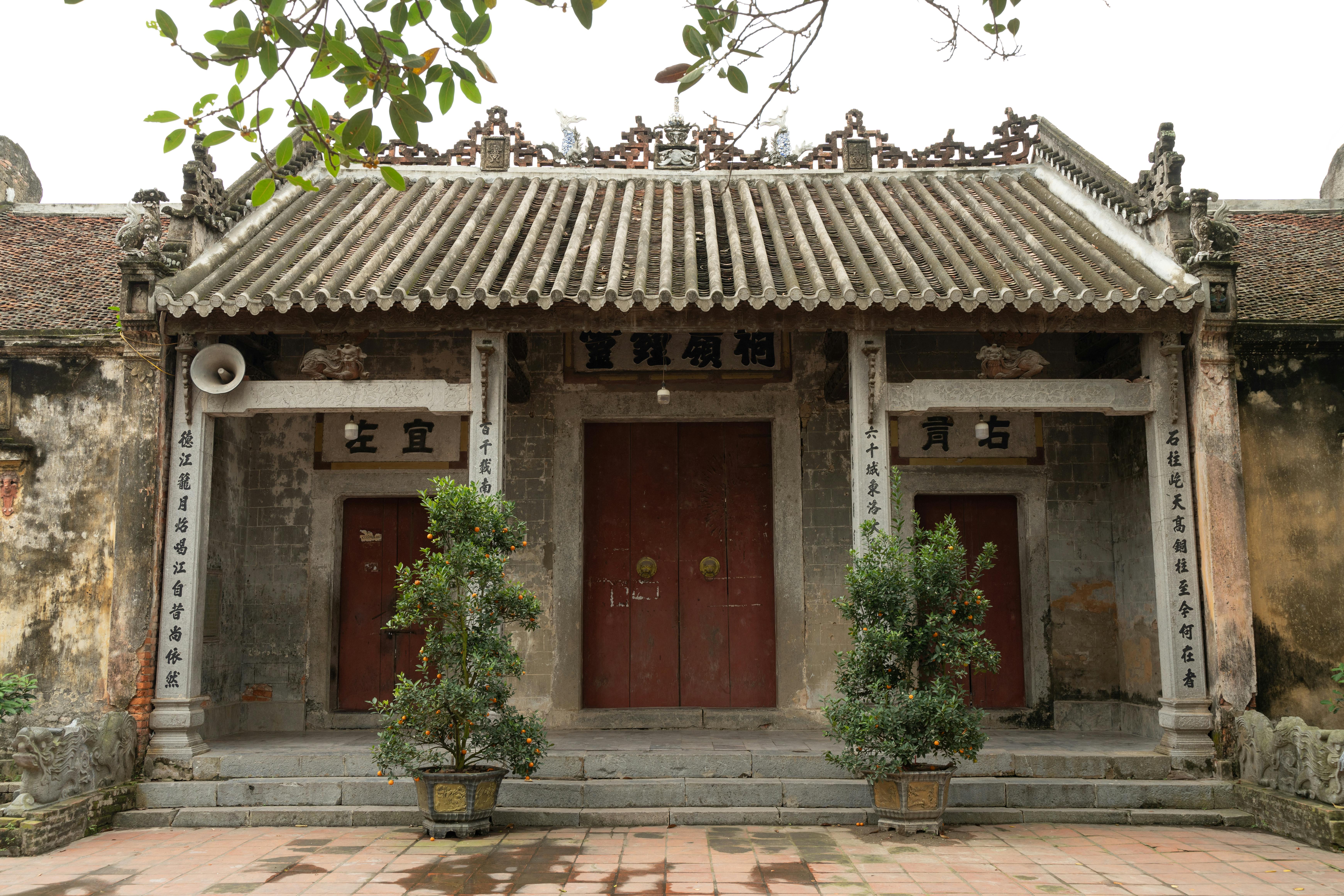 Historic temple entrance with traditional architecture and potted plants, ideal for cultural travel themes.