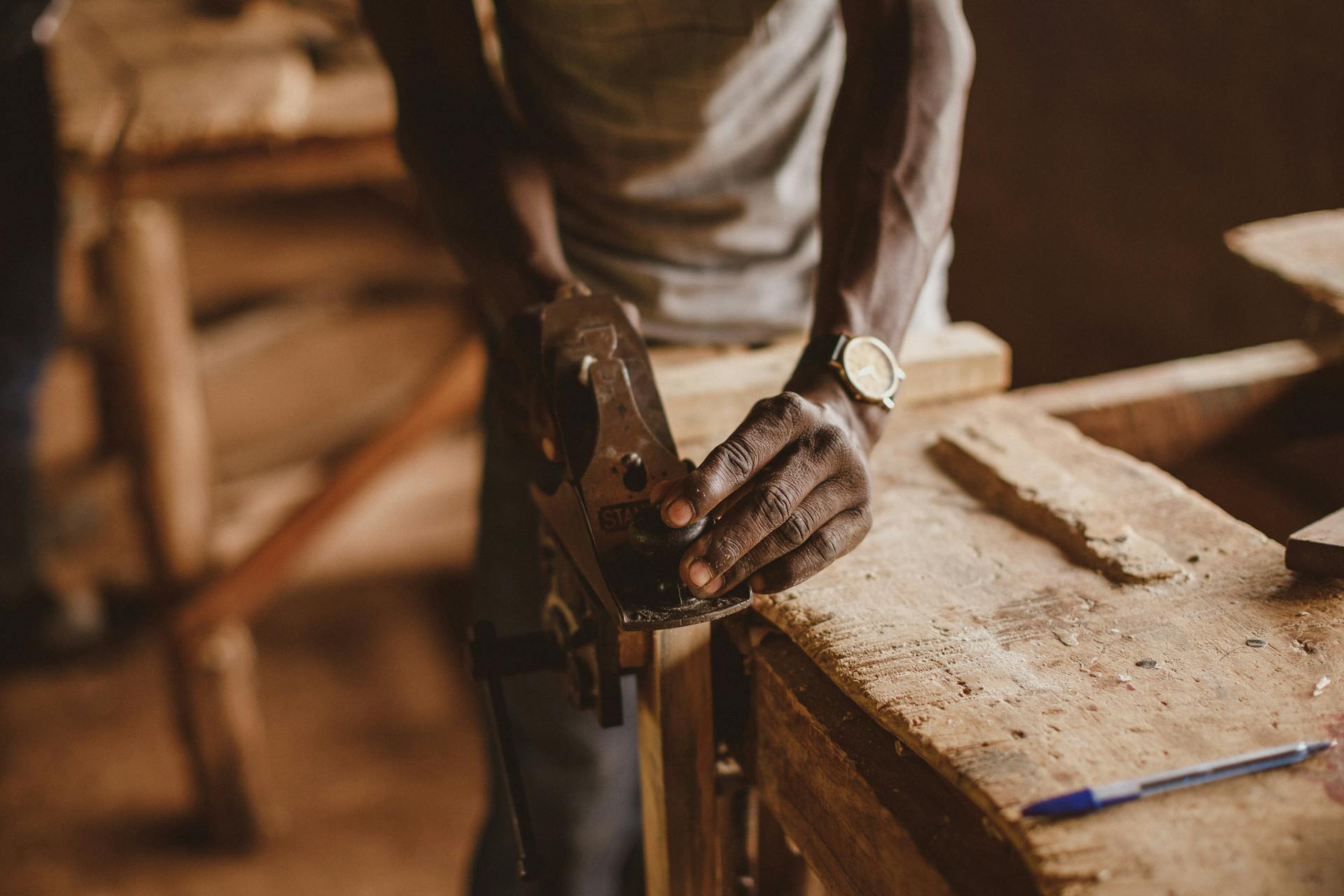 A skilled artisan focuses on metalwork craftmanship in a Ugandan workshop, emphasizing traditional techniques.