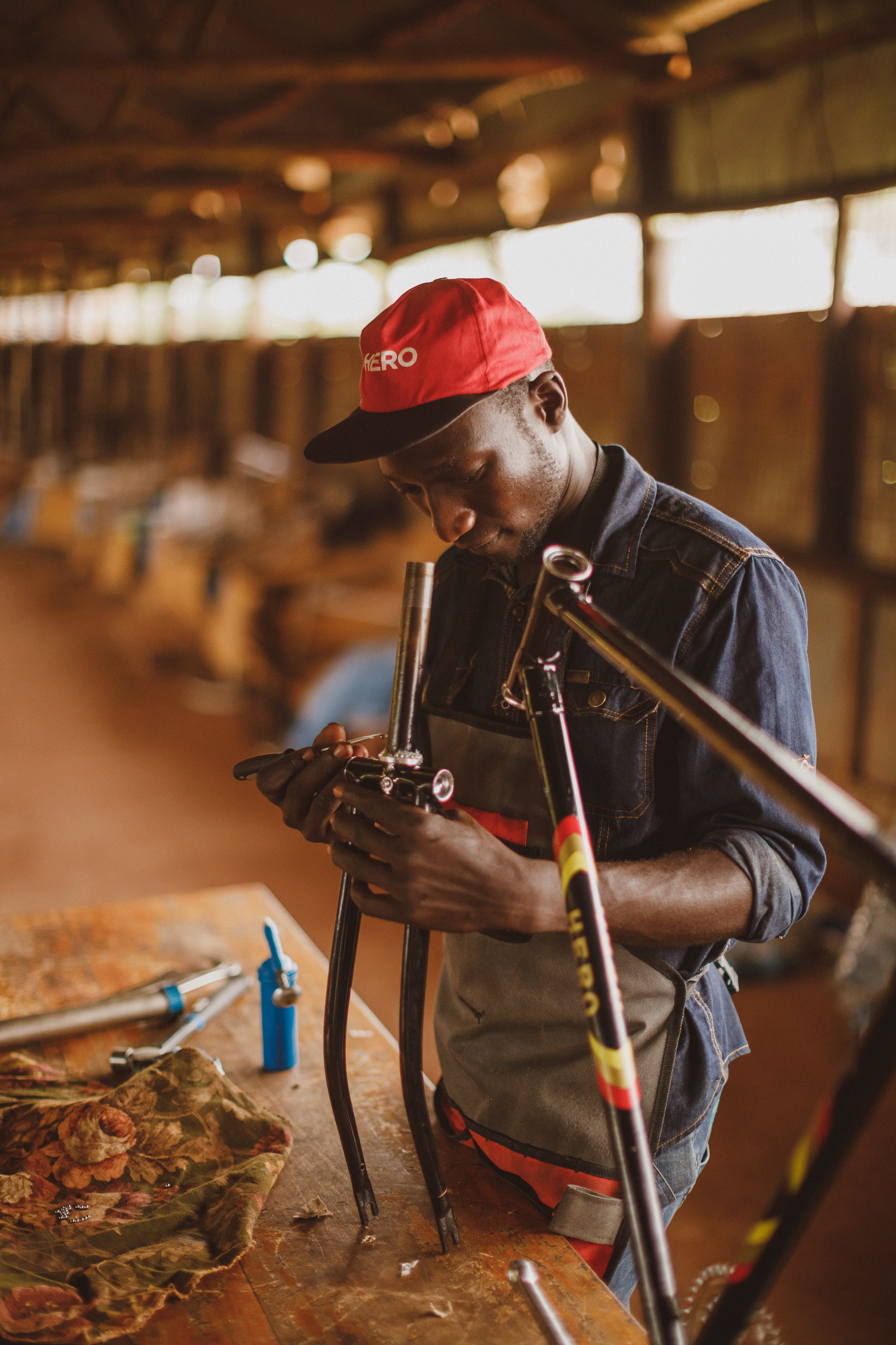 Male artisan focuses intently on bicycle assembly in an Ugandan workshop, showcasing skill and craftsmanship.