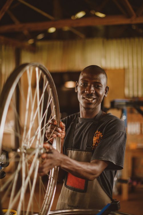 Free Portrait of a smiling man in a workshop handling a bicycle wheel, Gayaza, Uganda. Stock Photo