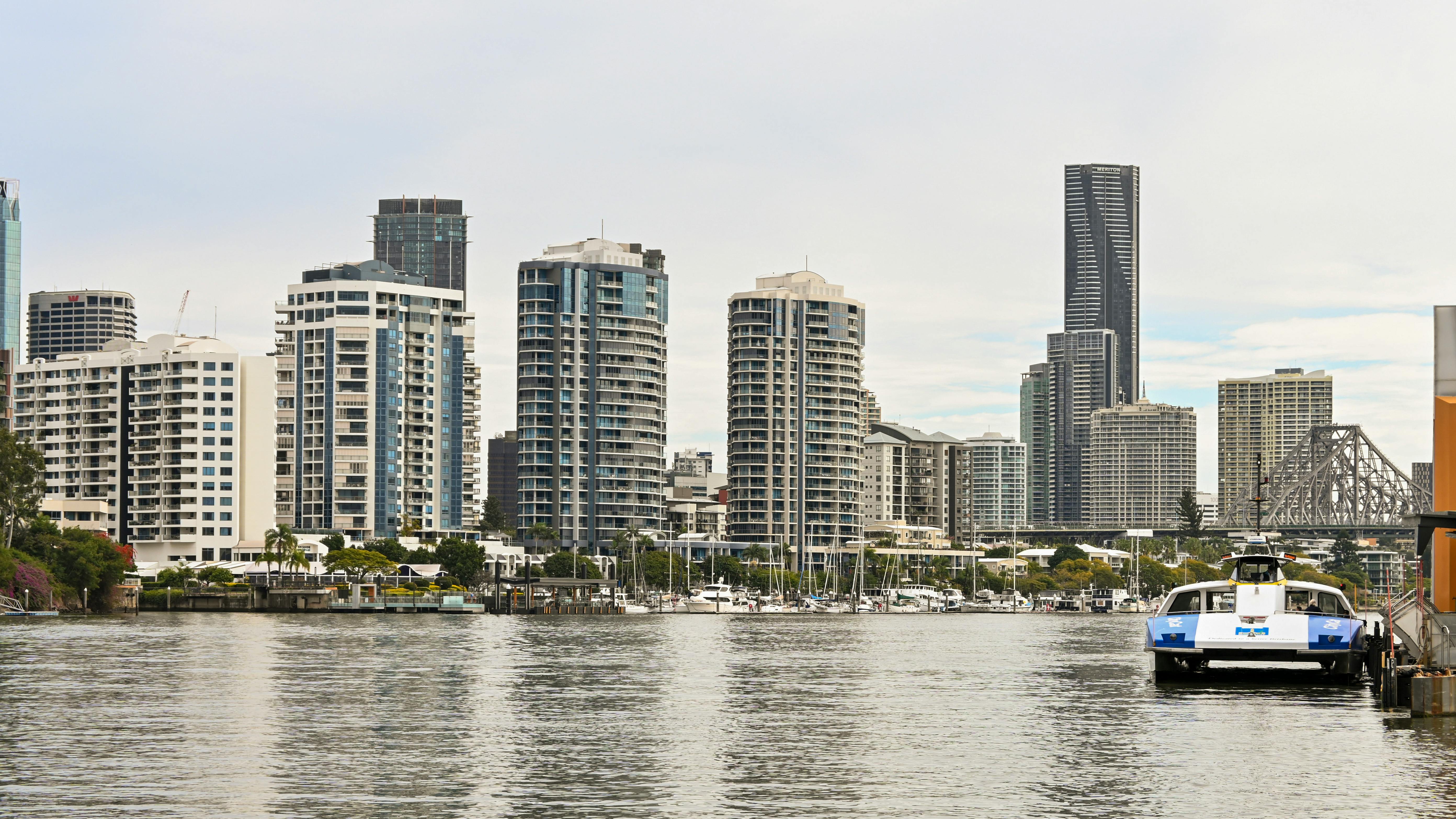 Contemporary urban skyline featuring tall buildings by the waterfront with a ferry docked nearby.