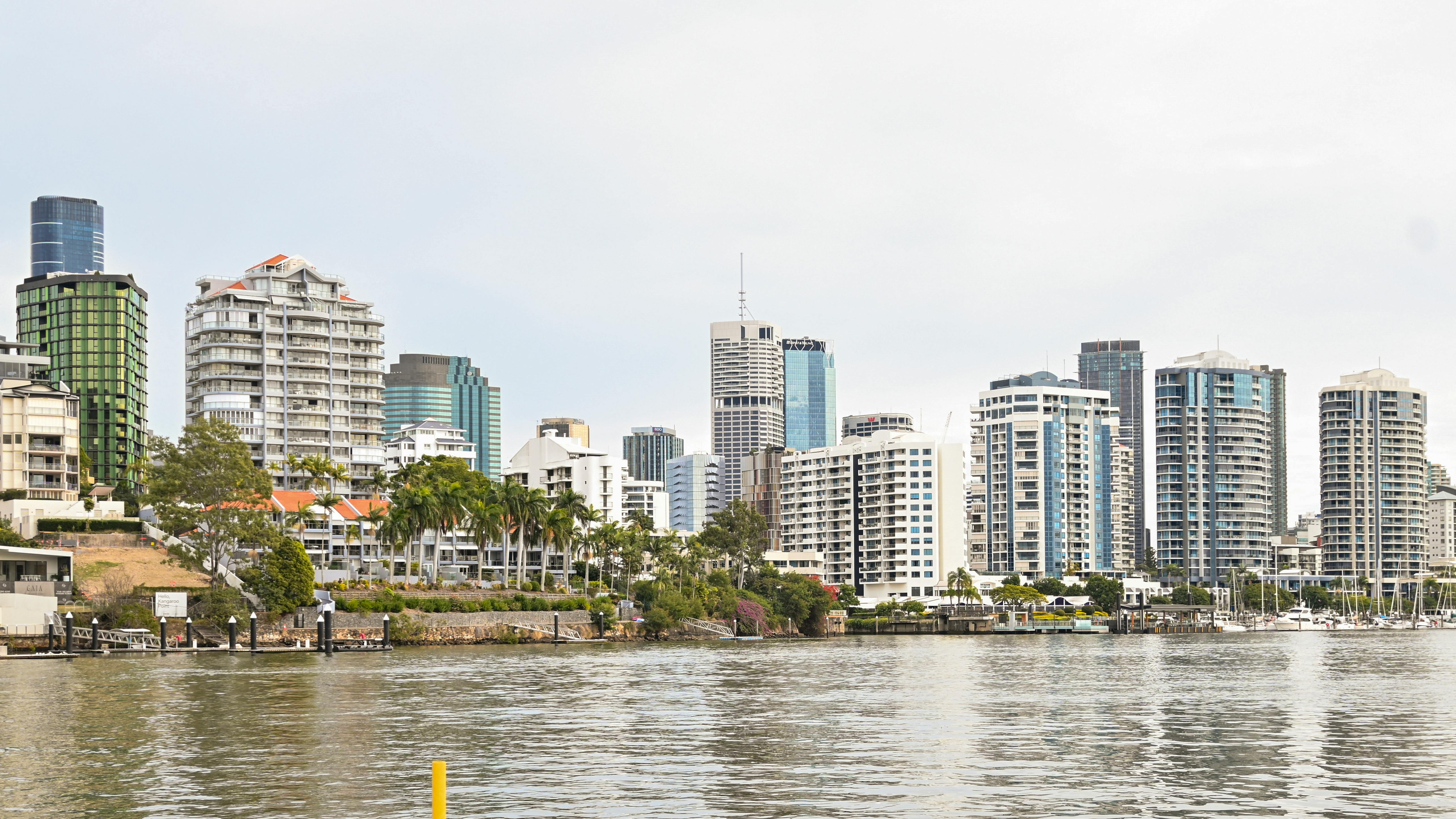 Panoramic view of Brisbane skyline with modern skyscrapers from riverfront perspective.