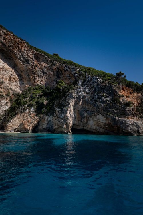 Free Majestic rocky cliff over turquoise waters under clear blue sky, ideal for travel inspiration. Stock Photo