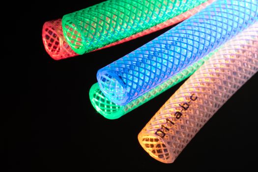 Vibrant illuminated mesh tubes in red, green, blue, and yellow against a dark background.