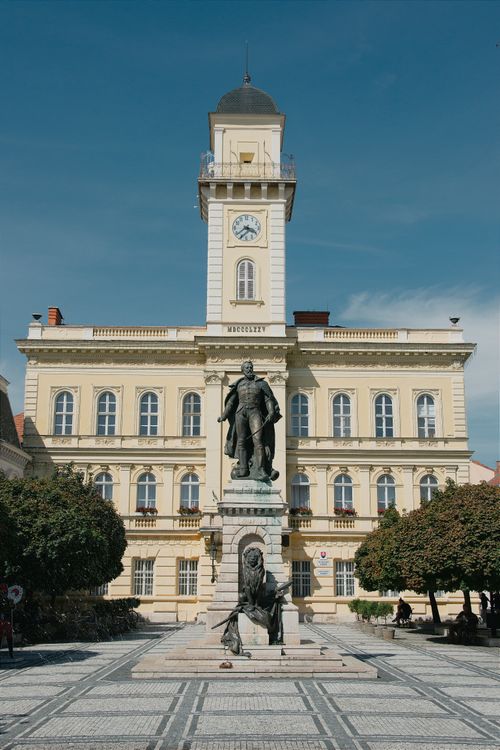 Free A stunning view of Komárno's historic town hall and statue under a bright blue sky. Stock Photo